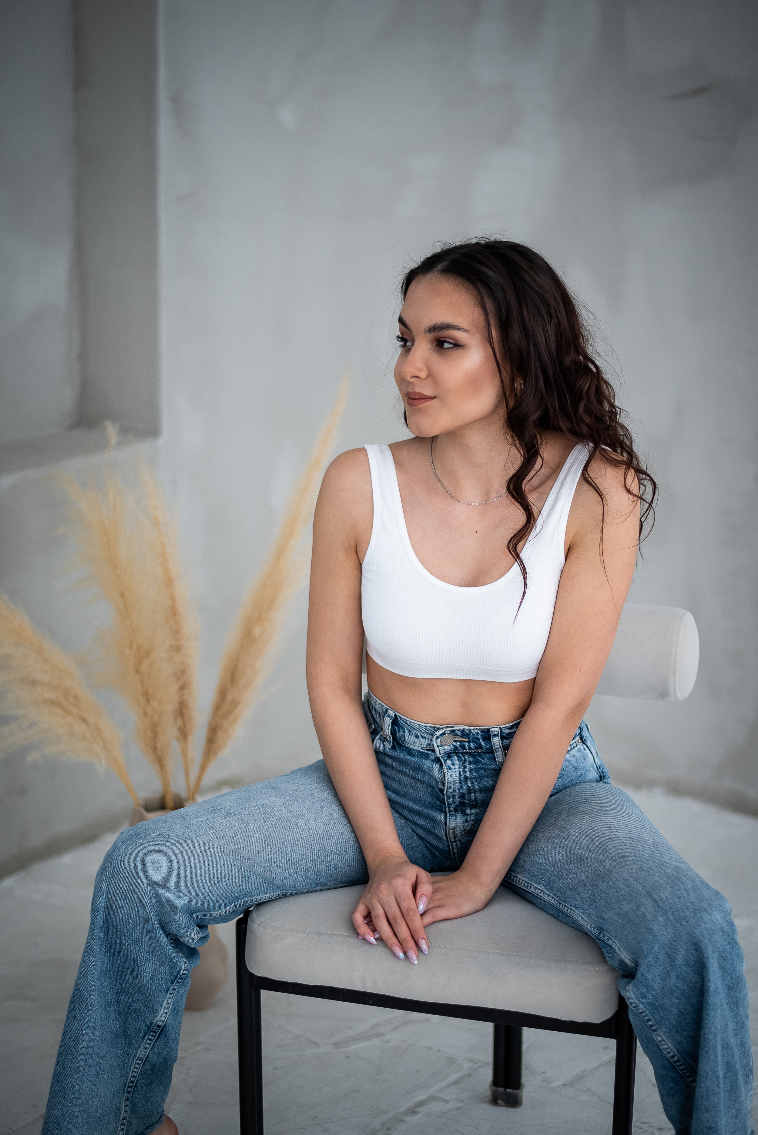 девушка сидя на стуле оперлась на руки, смотрит в сторону