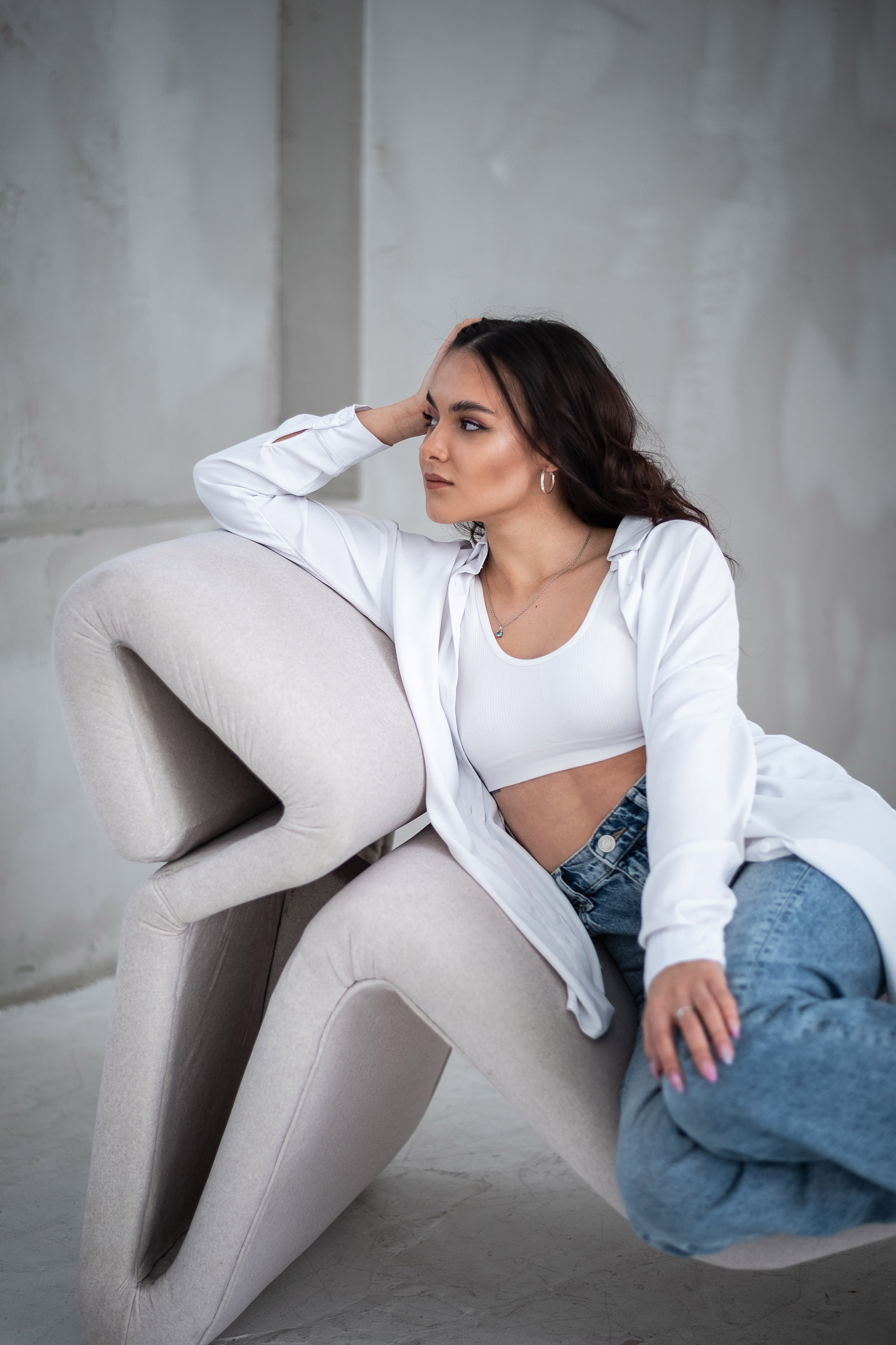 девушка с вьющимися  волосами сидит опираясь на руку 