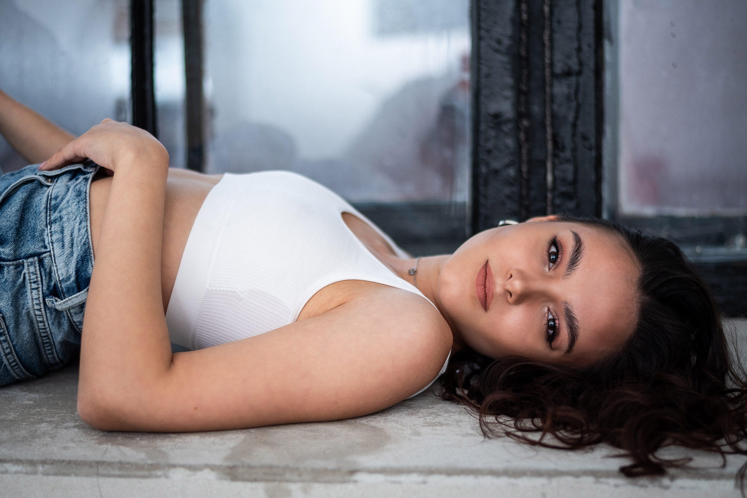 портрет девушки лежа на подоконнике крупным планом.