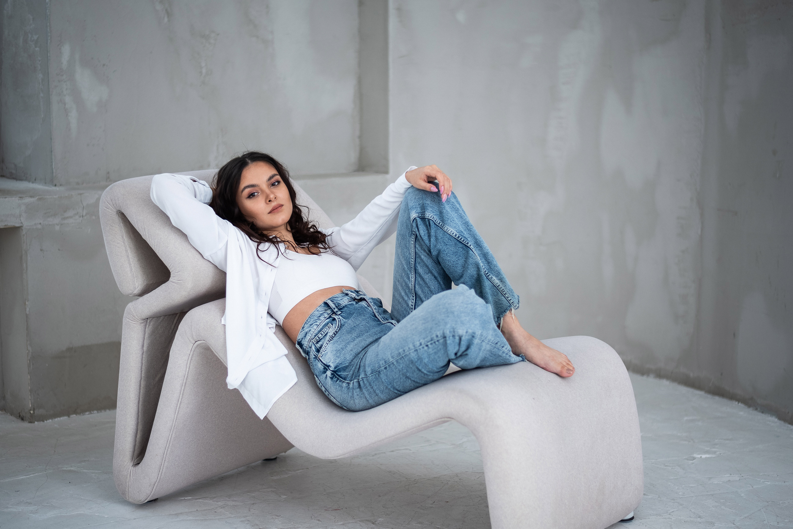 девушка в джинсах расположилась сидя на кушетке 