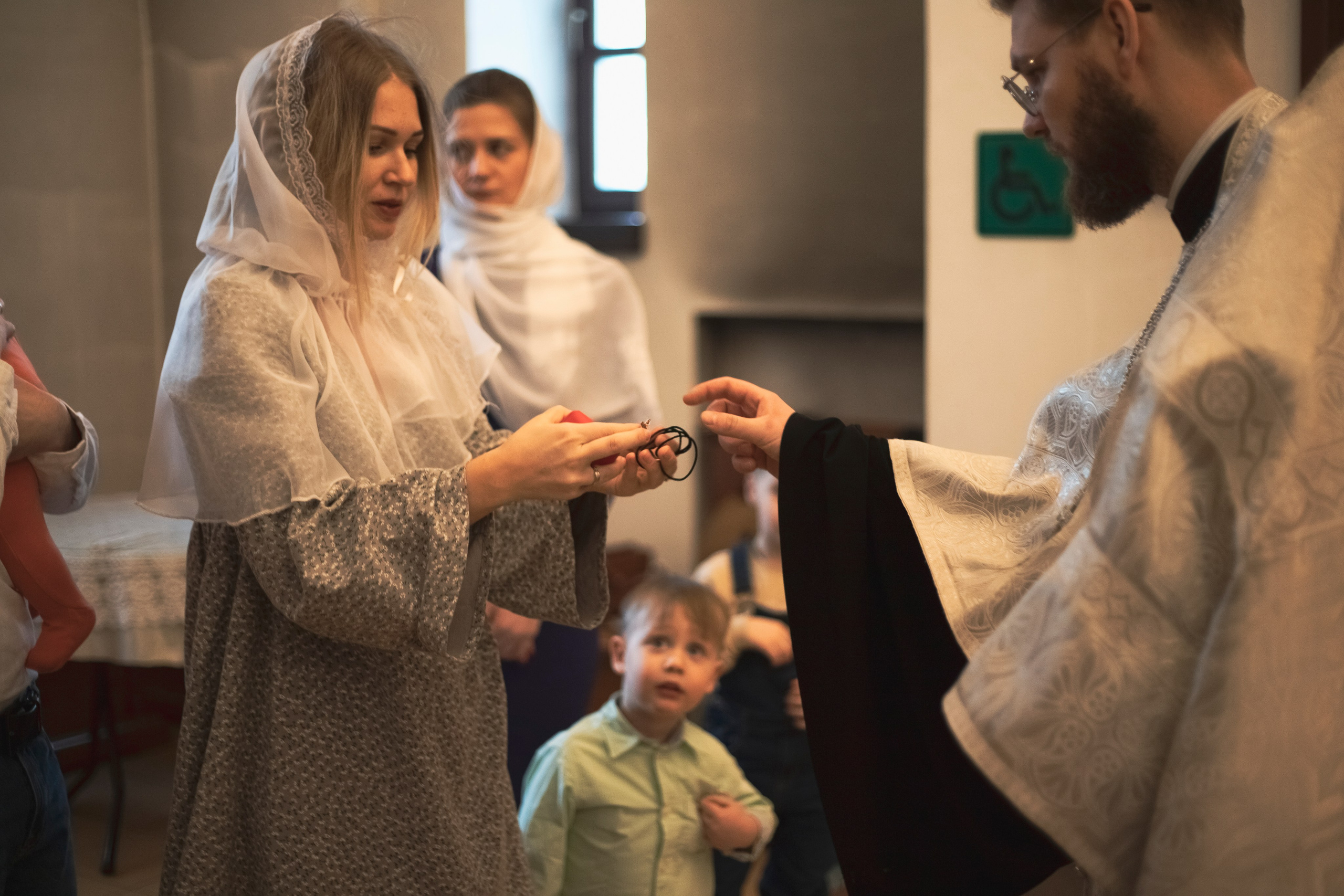 девушка передает батюшке крестик