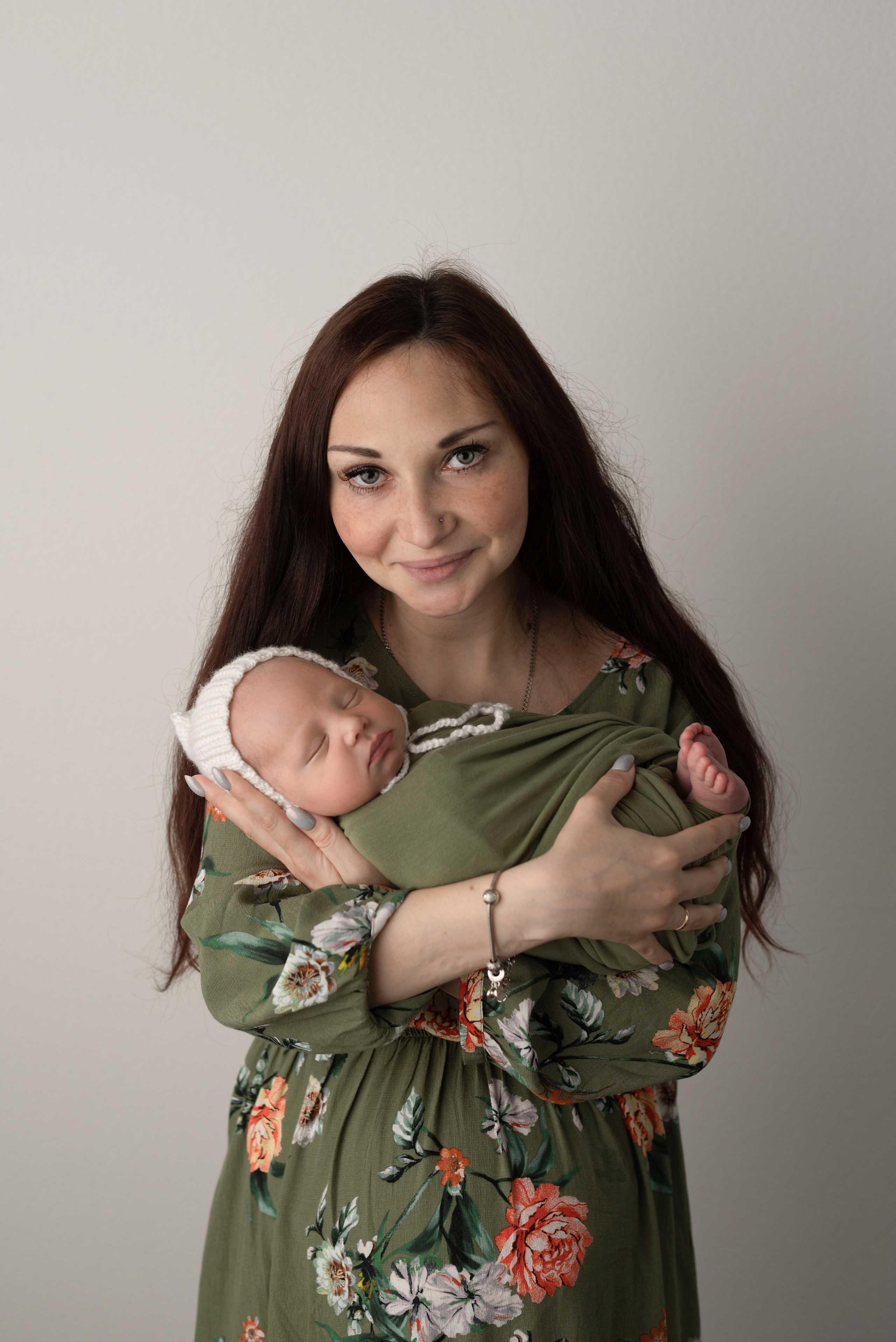 Baby in a white cap in his mother's hands