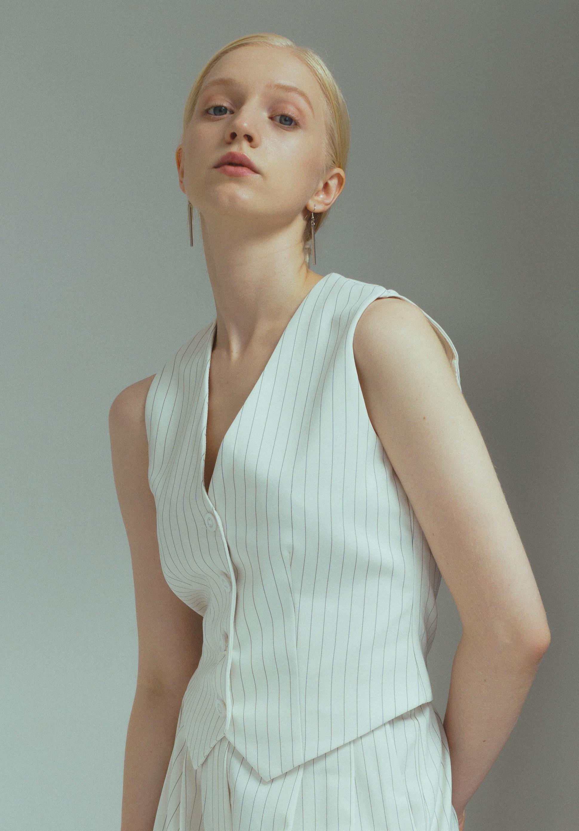 Девушка модель блондинка в белых брюках в полоску и жилете