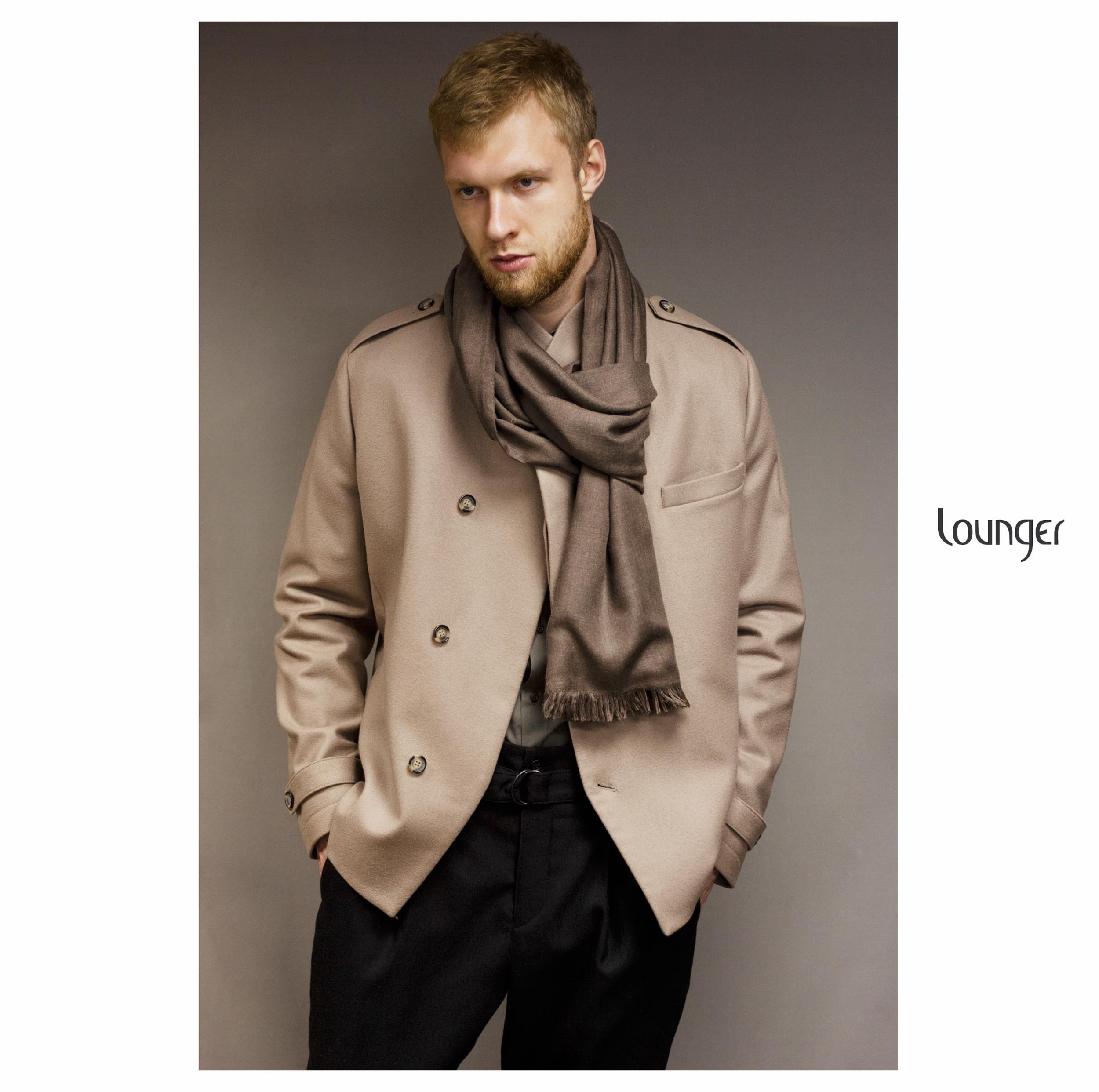 Парень с бородой с коричневом коротком пальто и шарфом