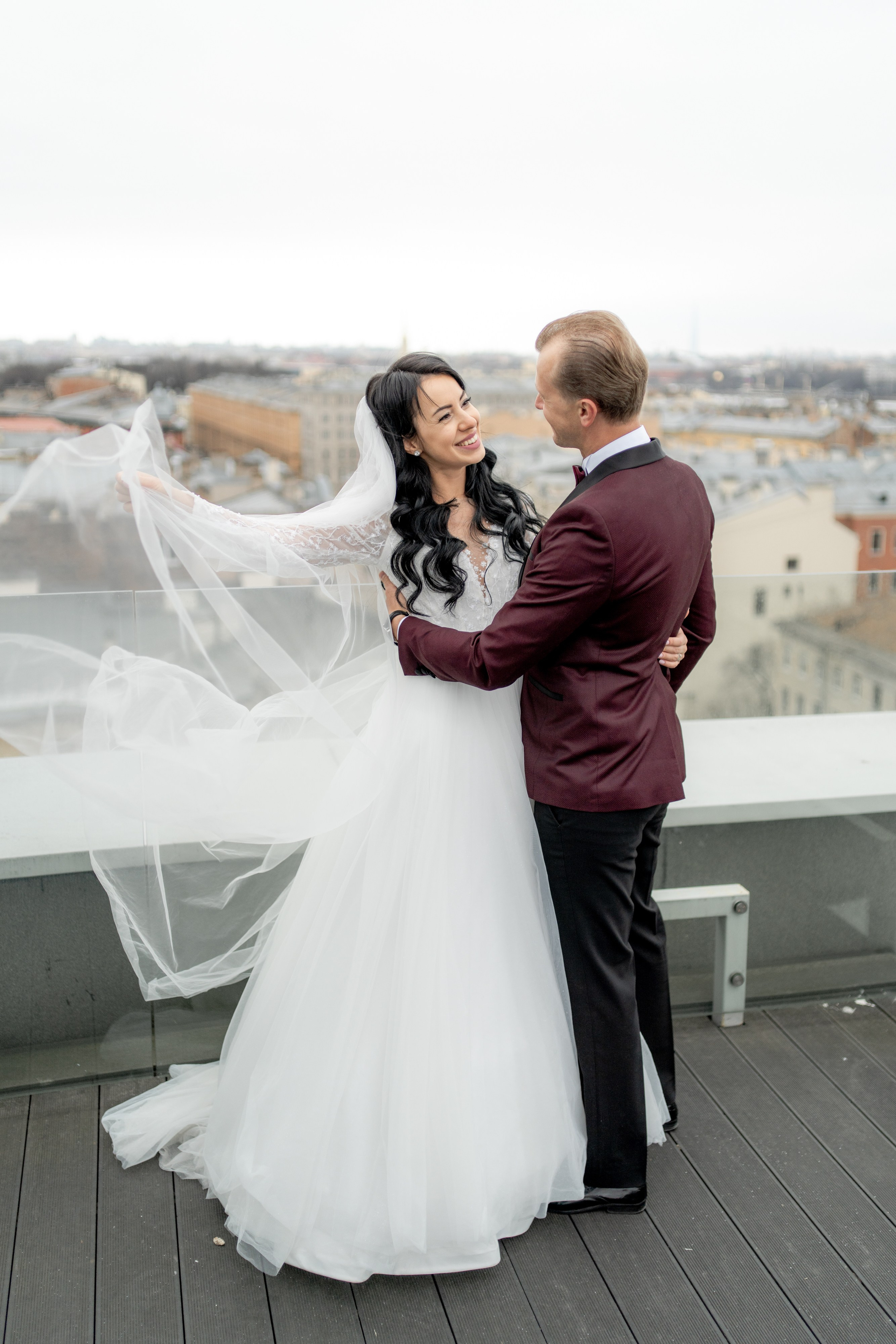невеста развивает на ветру фату на крыше в отеле Индиго на свадебной фотосессии