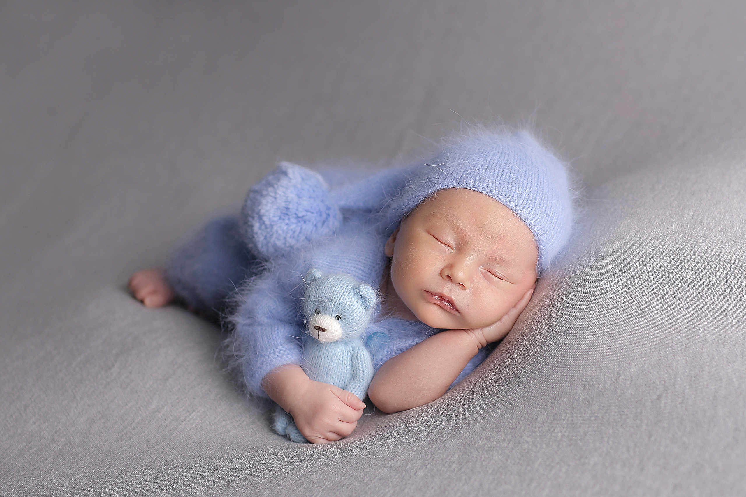 спящий новорожденный малыш в шапочке гномика и голубым медведем
