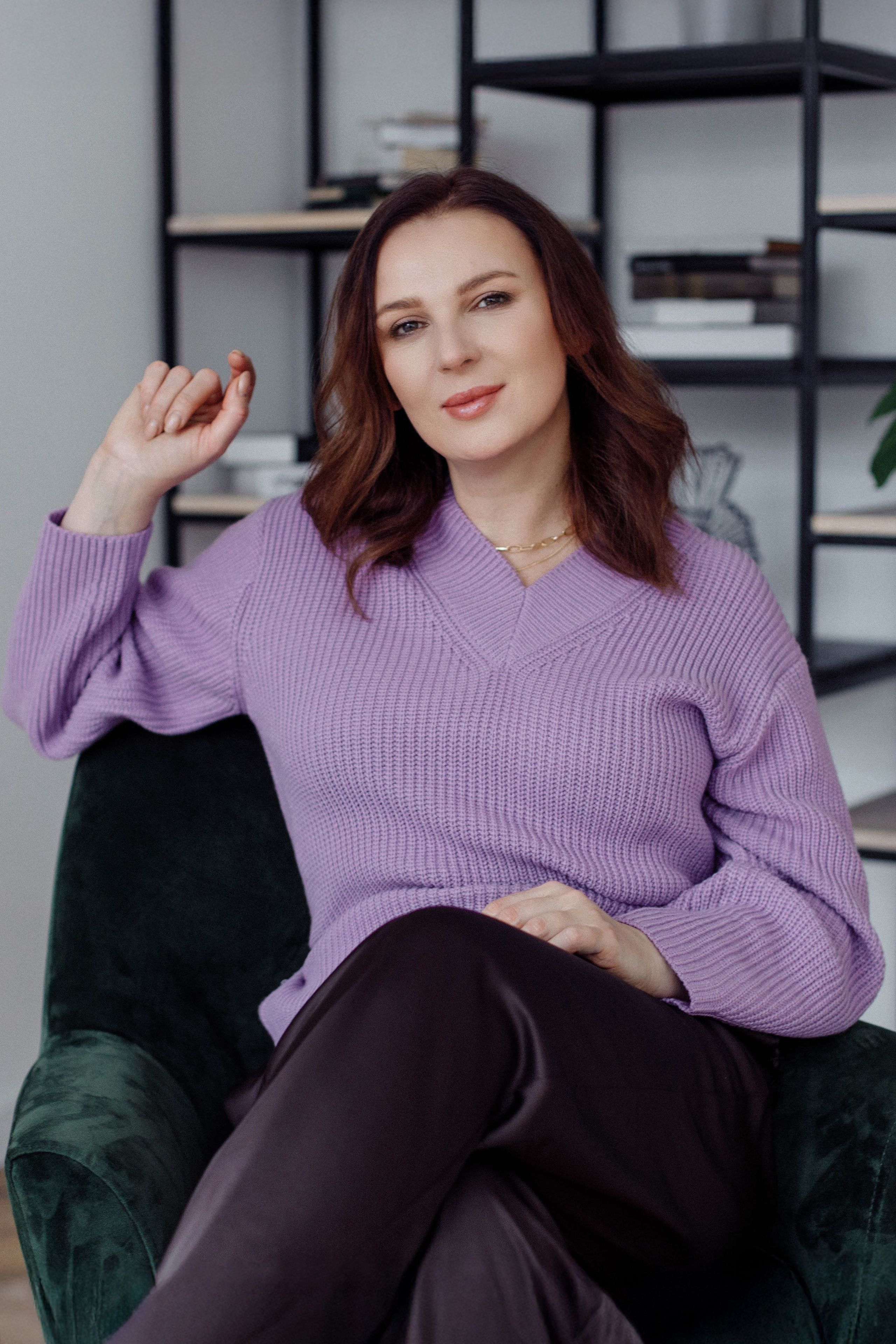 Лайфстайл-кадр в студии: психолог расслабленно сидит в кресле в интерьерной обстановке.