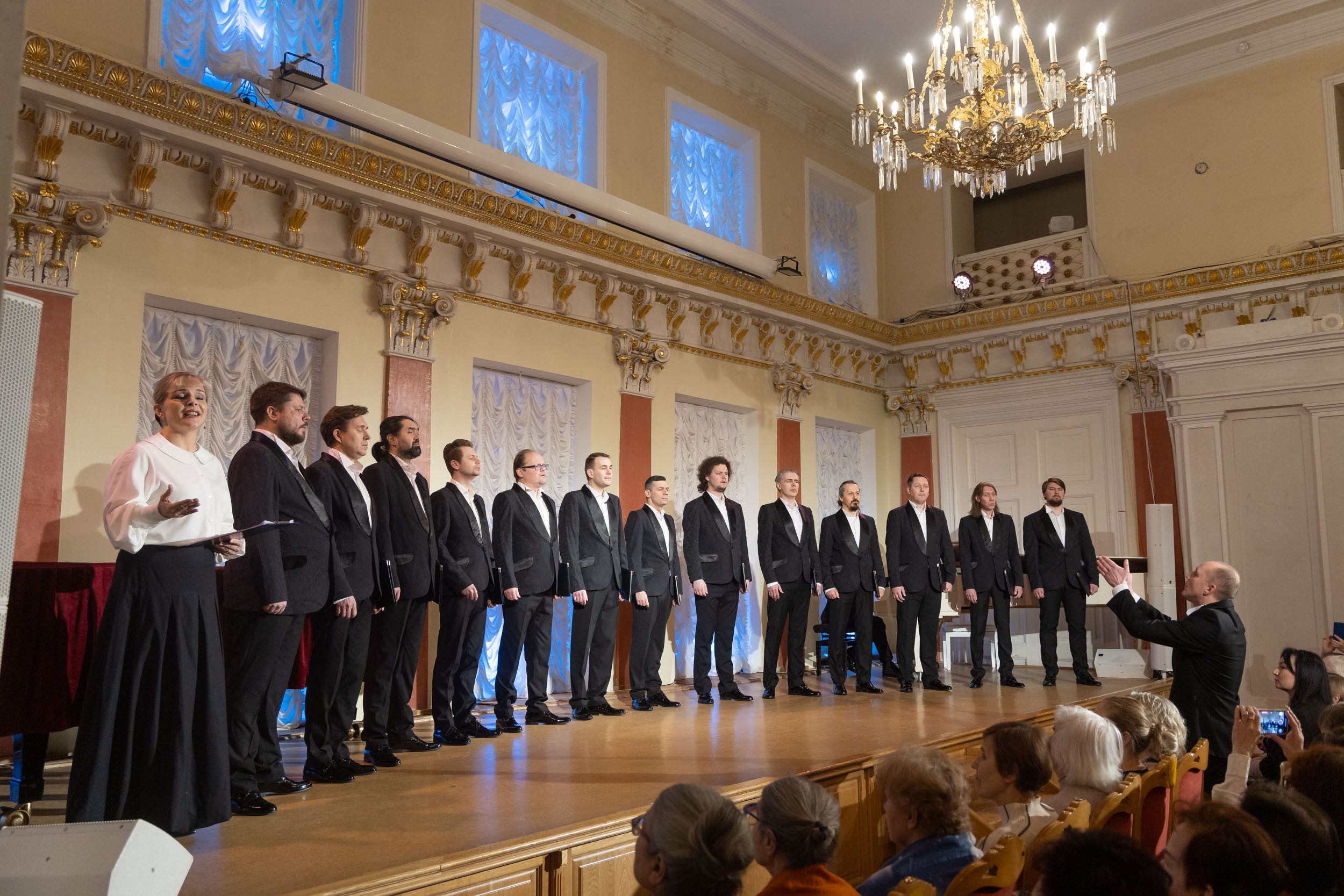 Мужской хор на сцене под управлением дирижера