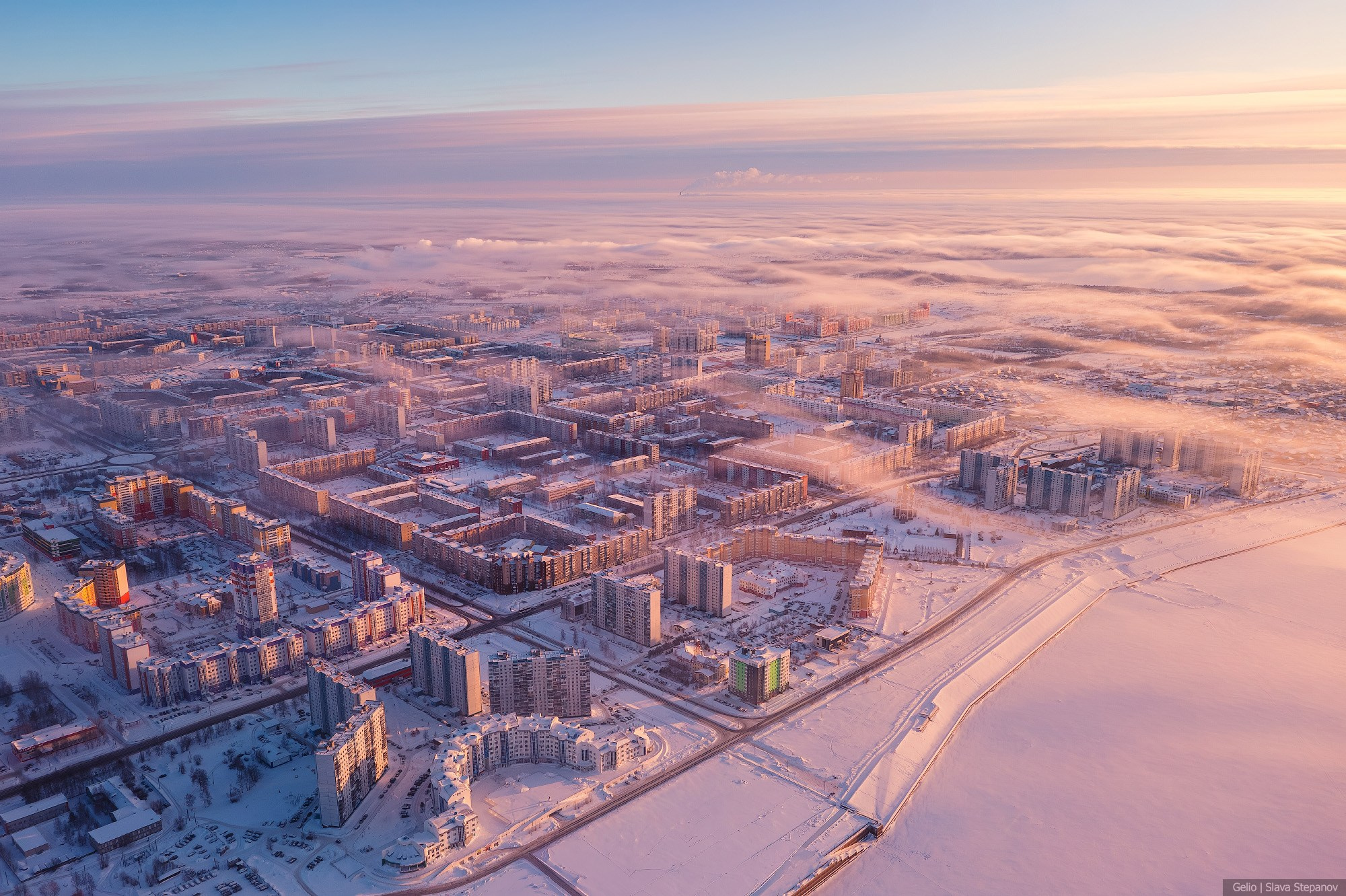 Заснеженные жилые районы северного города Нижневартовск в лучах розового зимнего утра, масштабная аэрофотосъемка застройки.