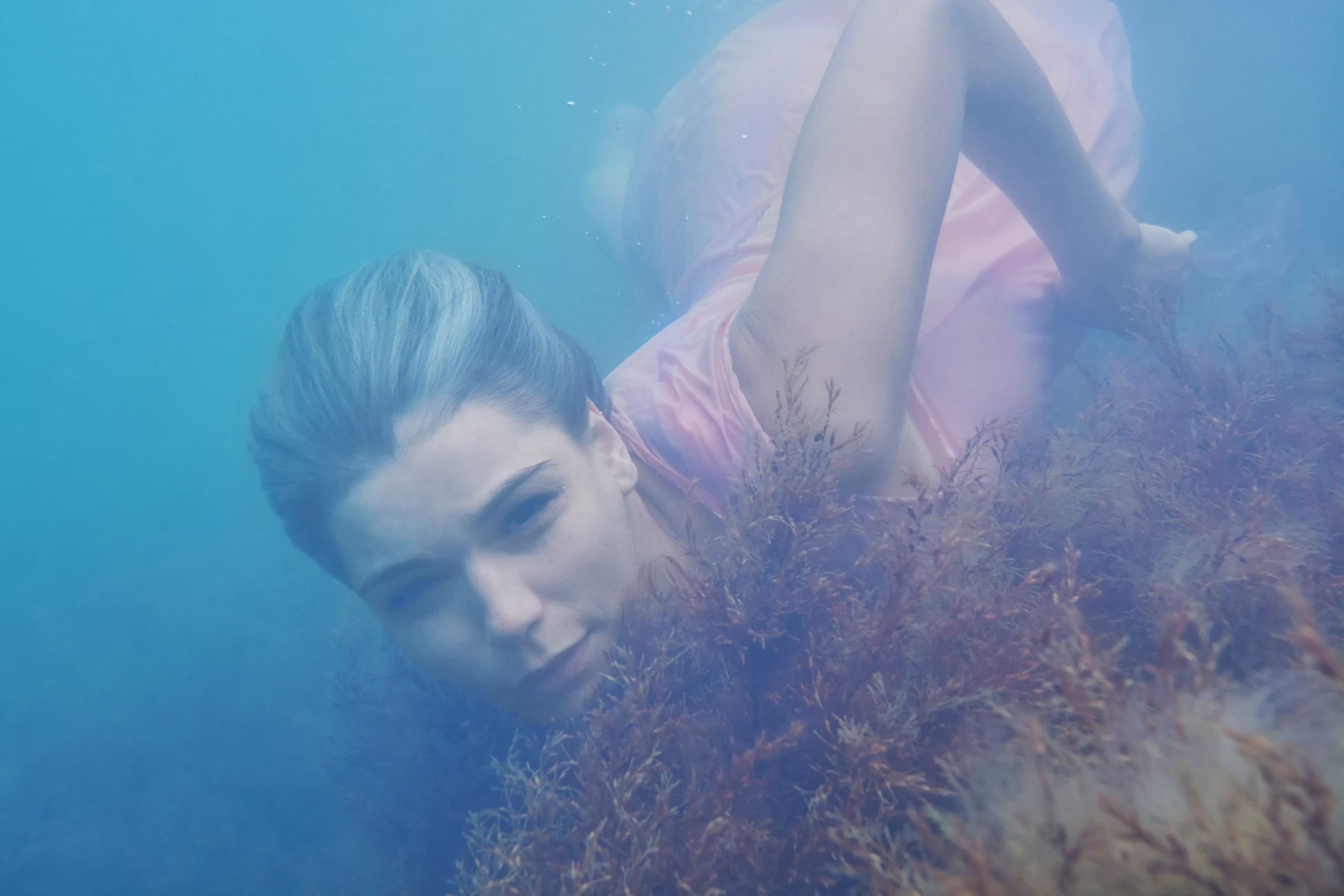 Девушка в розовом платье плывет под водой