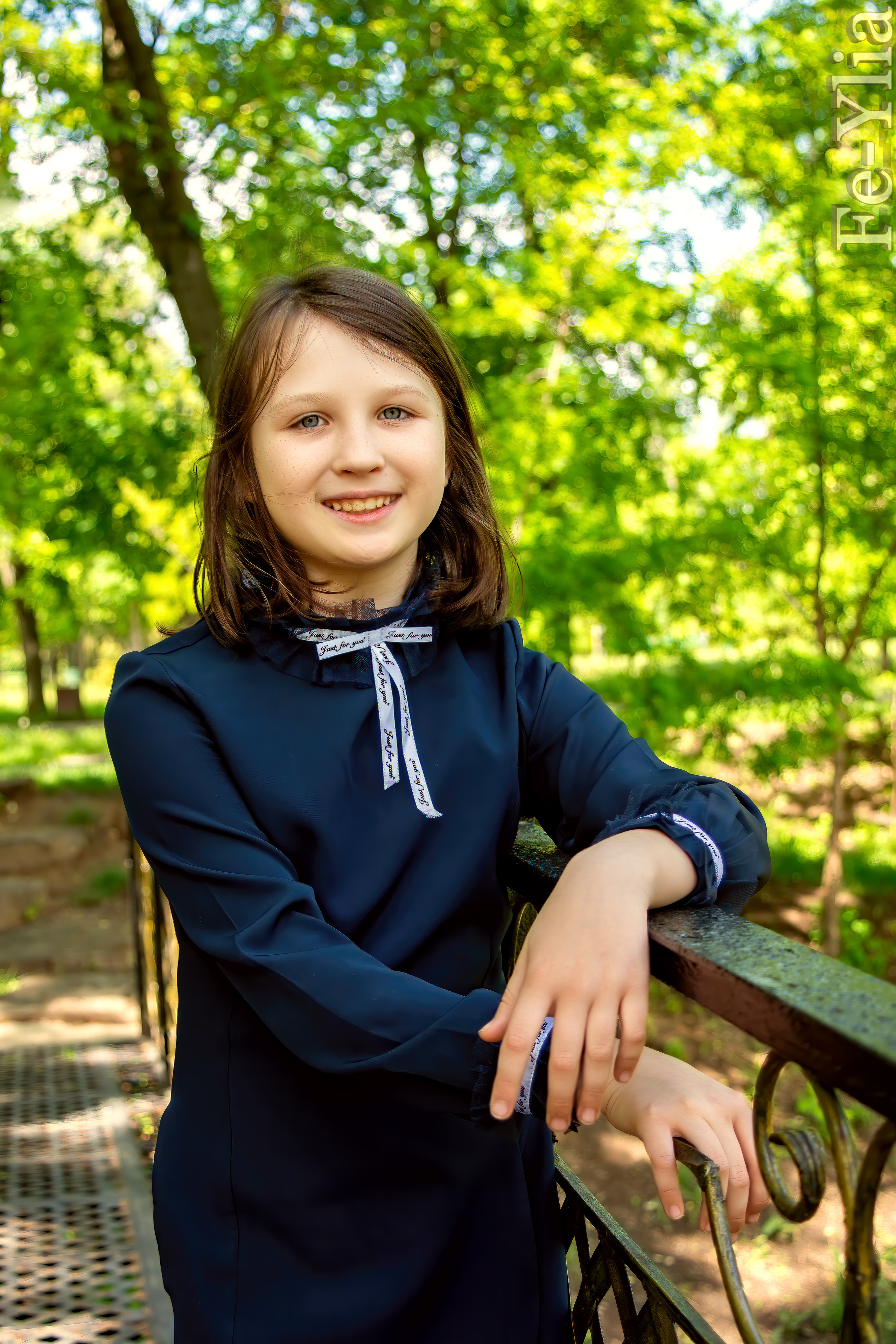 девочка  в парке стоит и опирается на перила