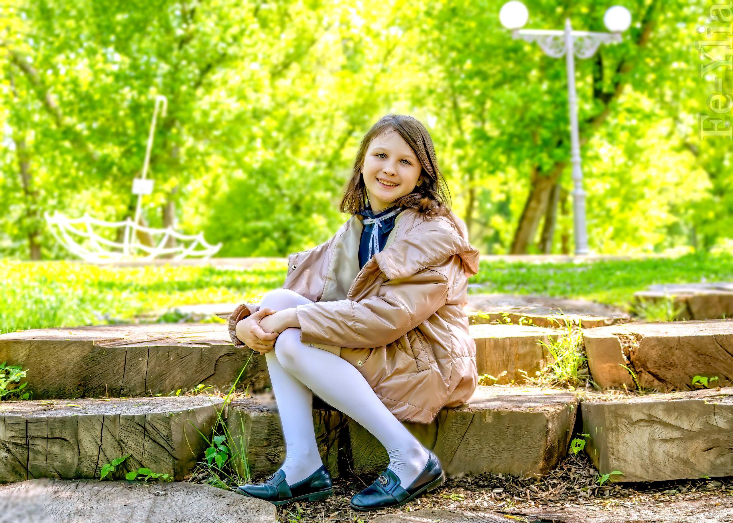 Девочка сидит в парке на деревянных ступеньках