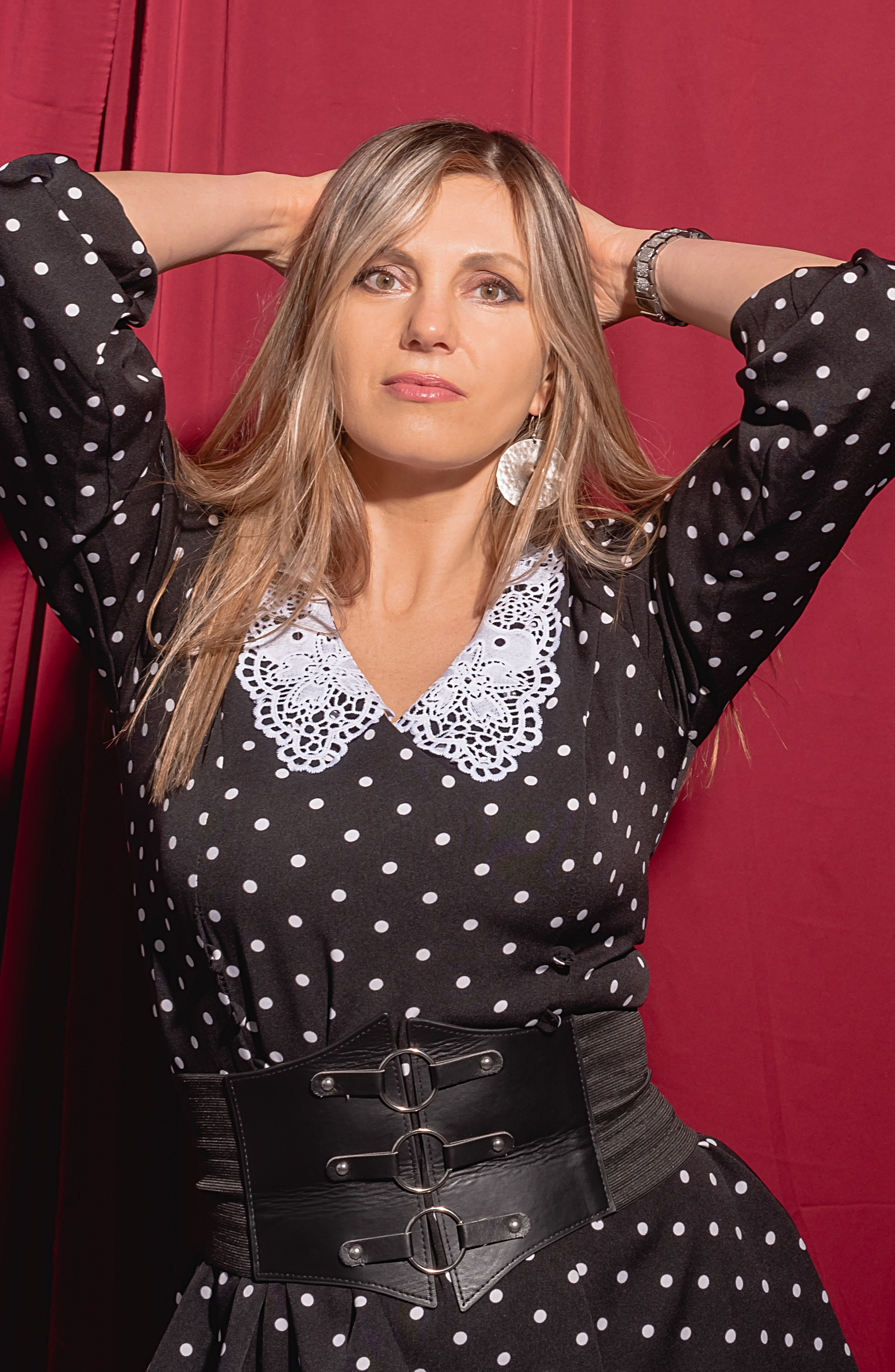 Фотография девушки на красном фоне в черном платье.