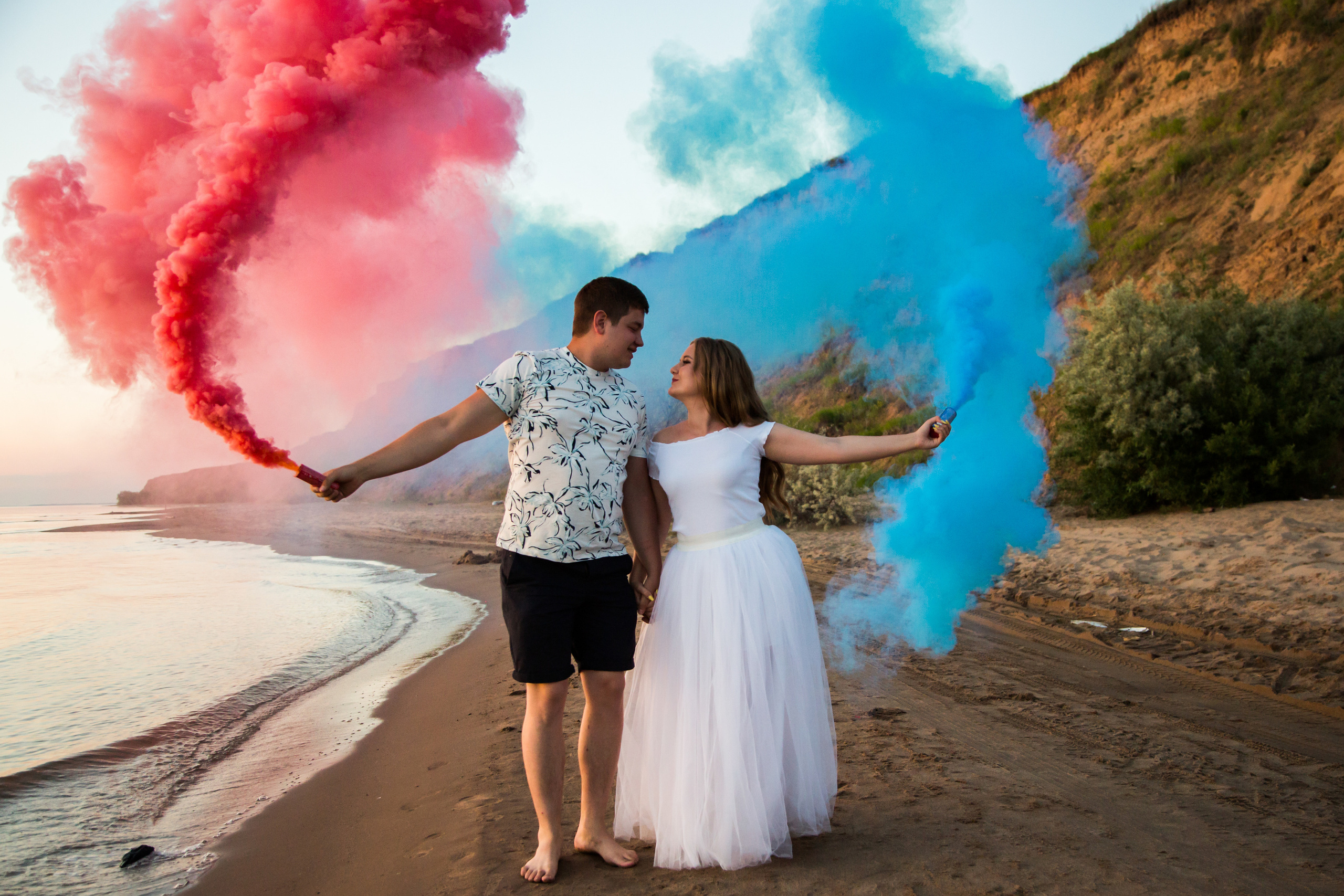 юноша и девушка с цветным дымом на фоне горы и моря