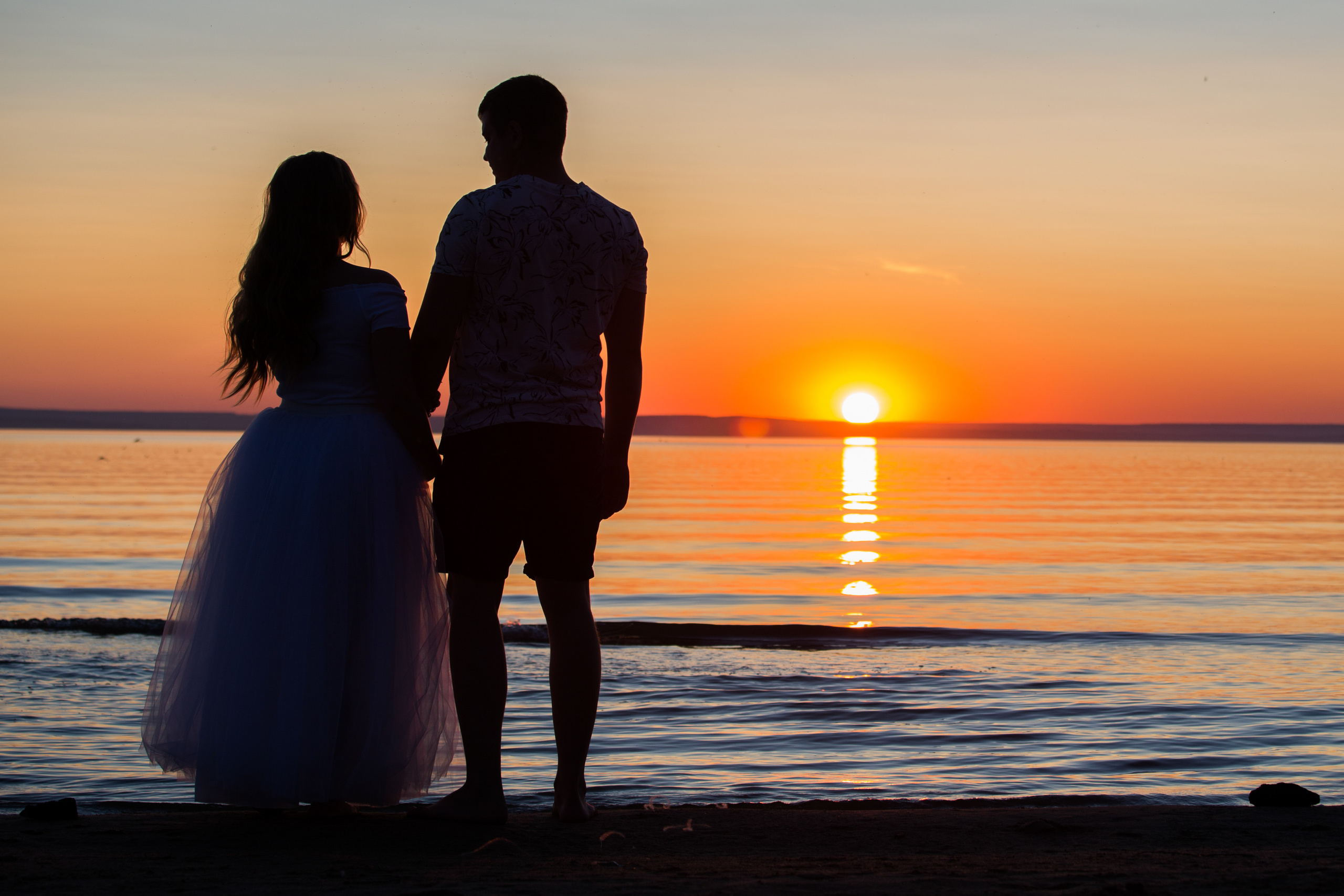 молодая пара провожают закат на море