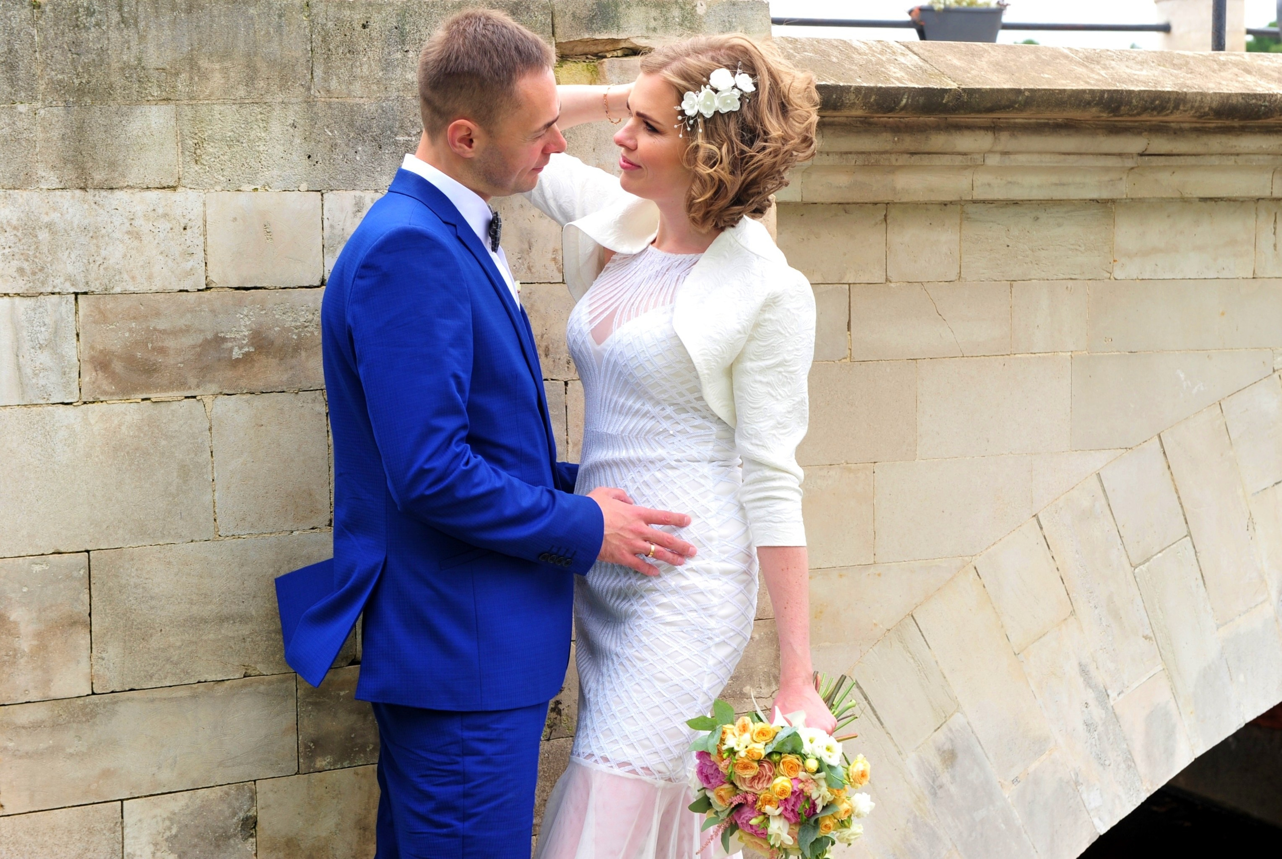 Свадьба в Царицыно хмурым прохладным летним днём, молодожены стоят у белого каменного моста в парке