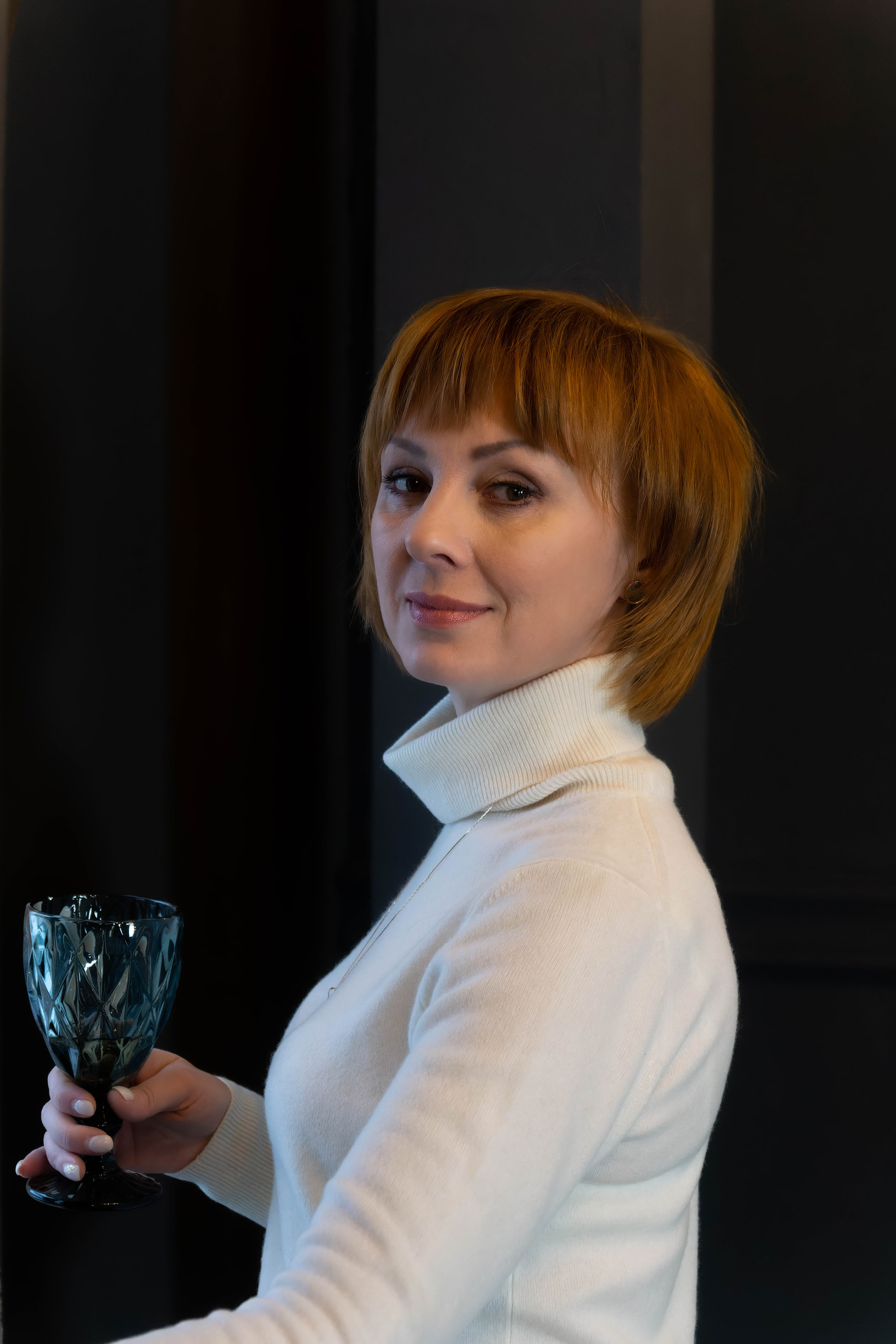 Портрет молодой женщины с бокалом вина в руках, стоящей в пол оборота к фотографу Элле Тев