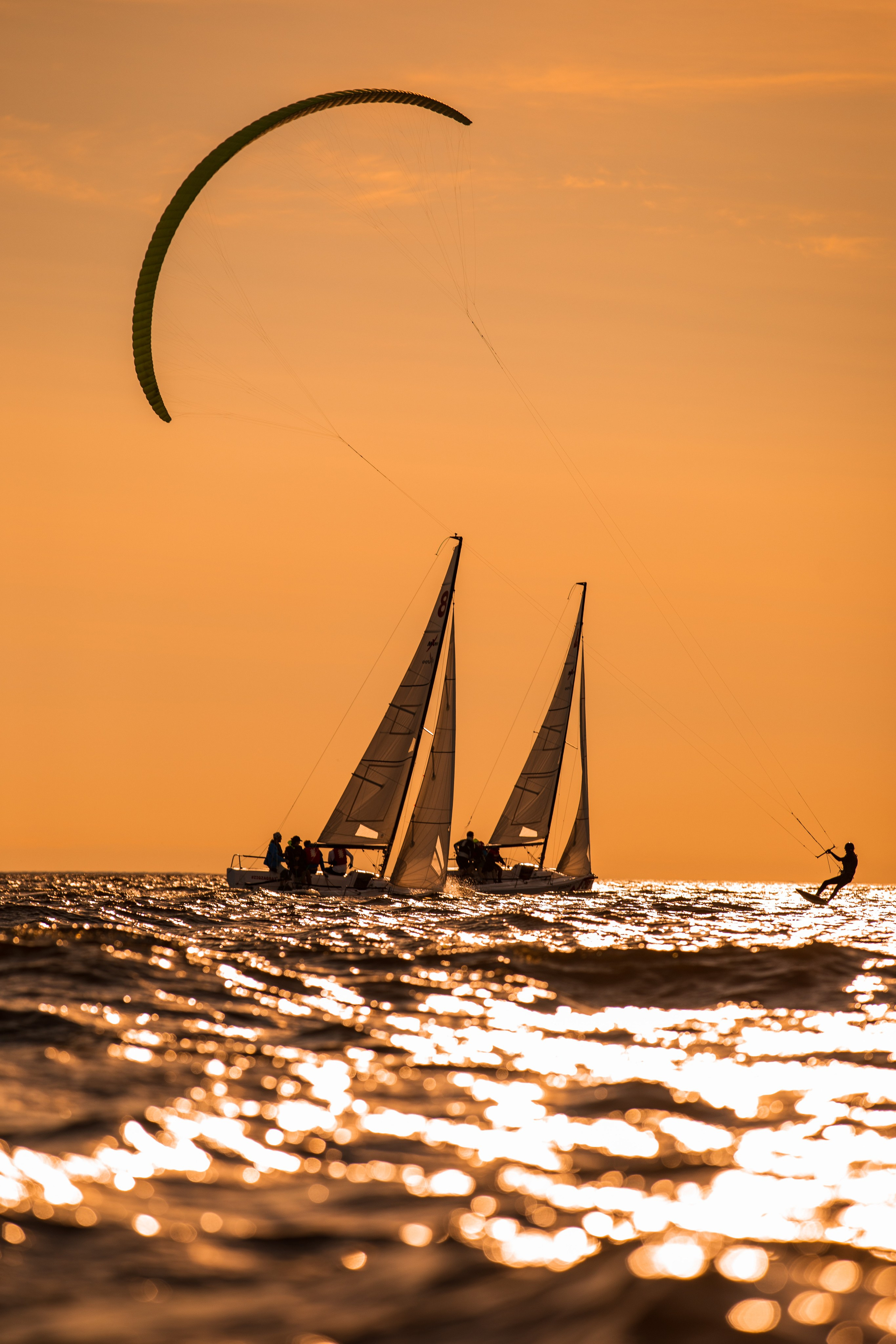 Две парусные яхты и кайтсерфер на закате на Финском заливе.