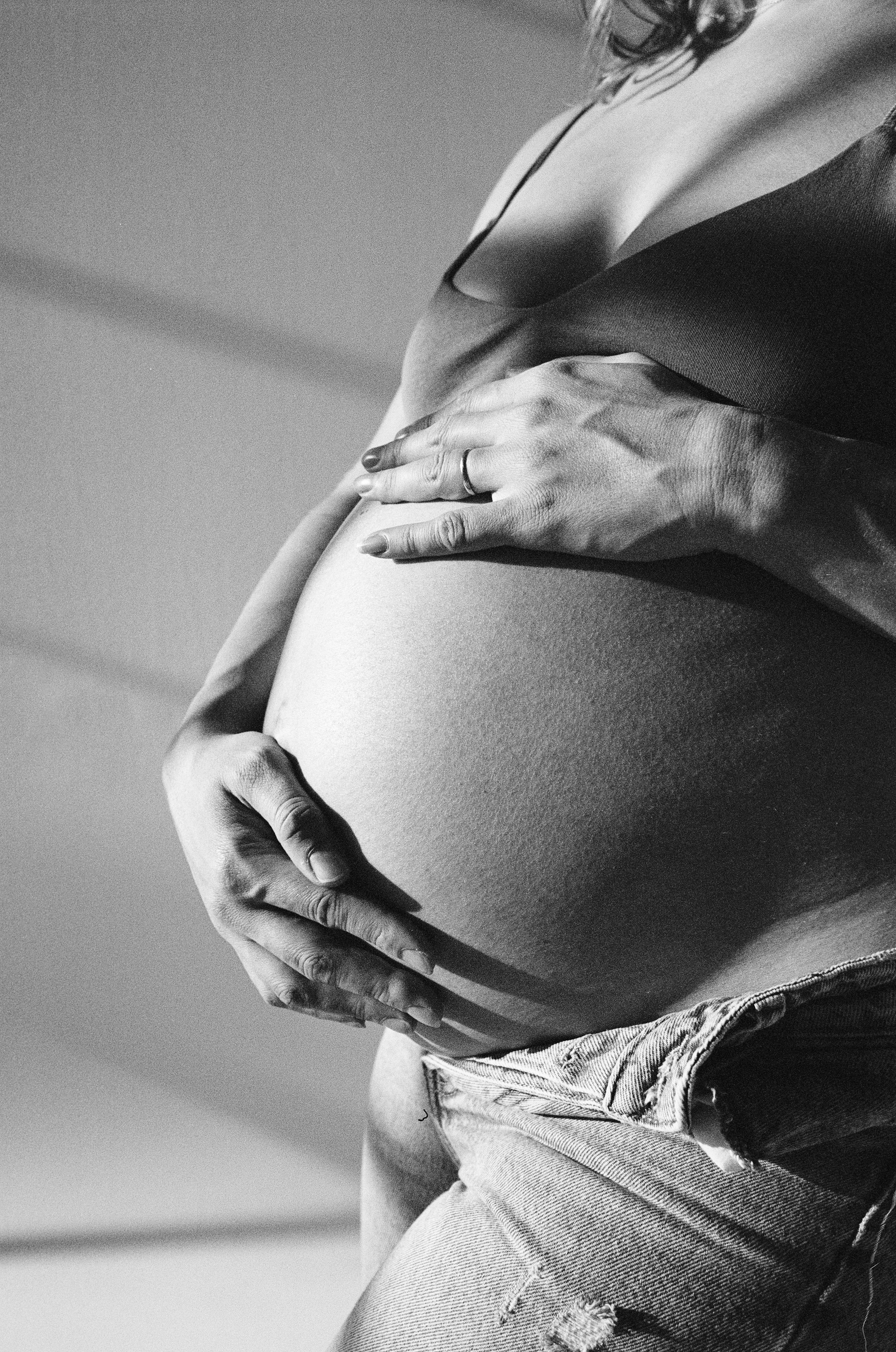 a black and white film photo of a mom to be holding the belly
