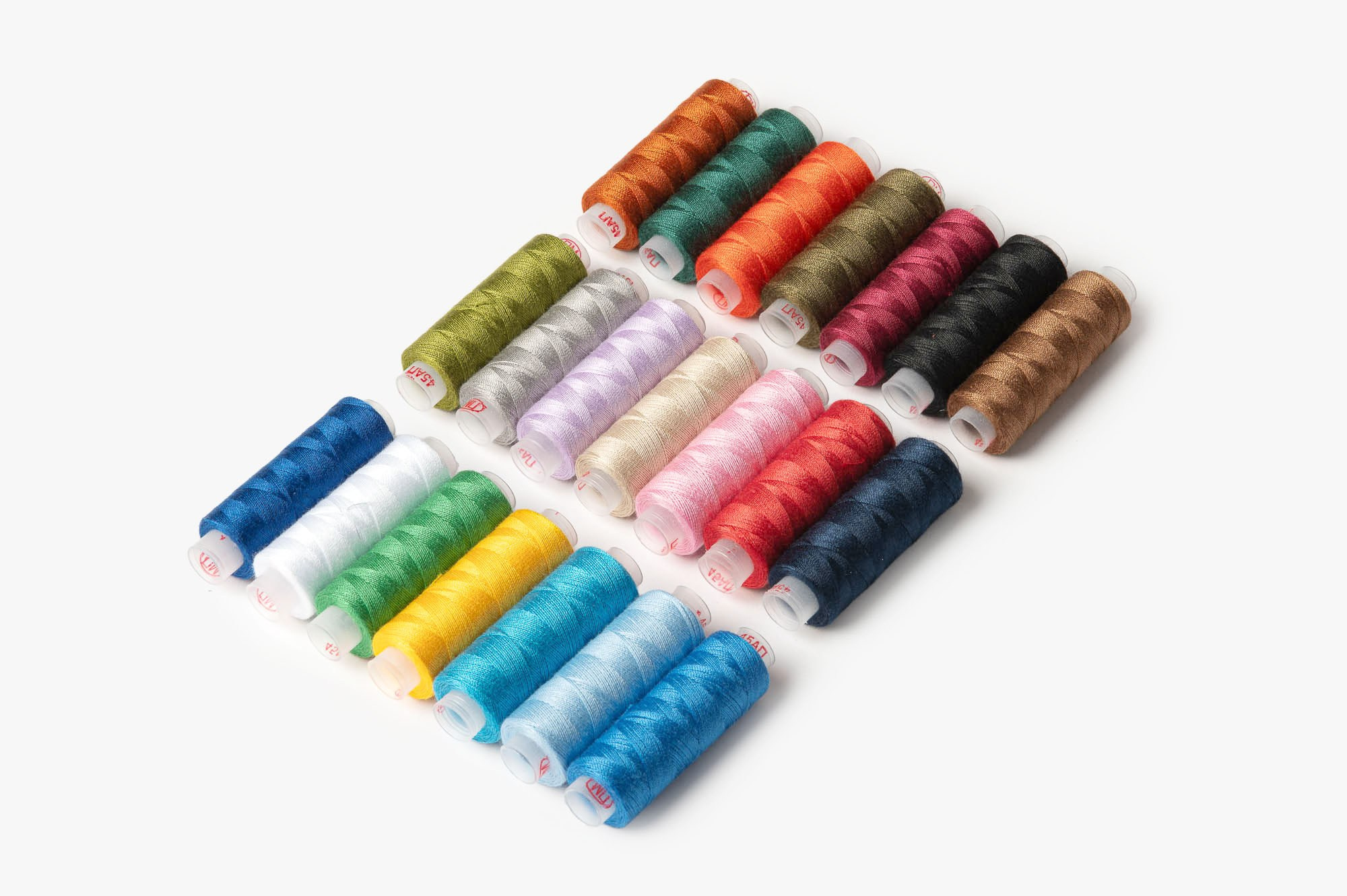 Набор разноцветных катушек ниток на белом фоне — предметная съемка товаров для шитья.