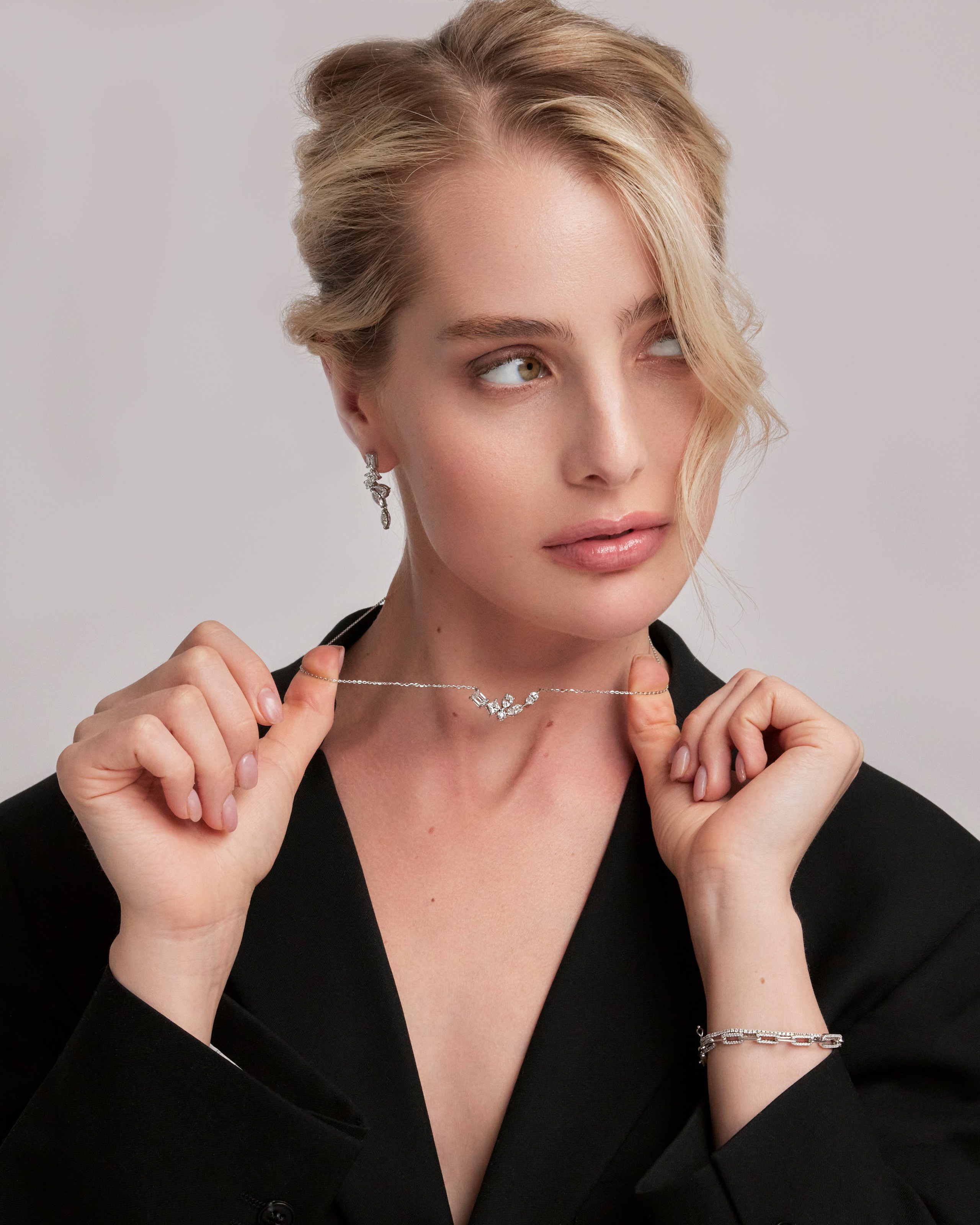 Blonde model wearing stacked gold rings and matching earrings, highlighting luxury jewelry for formal occasions.