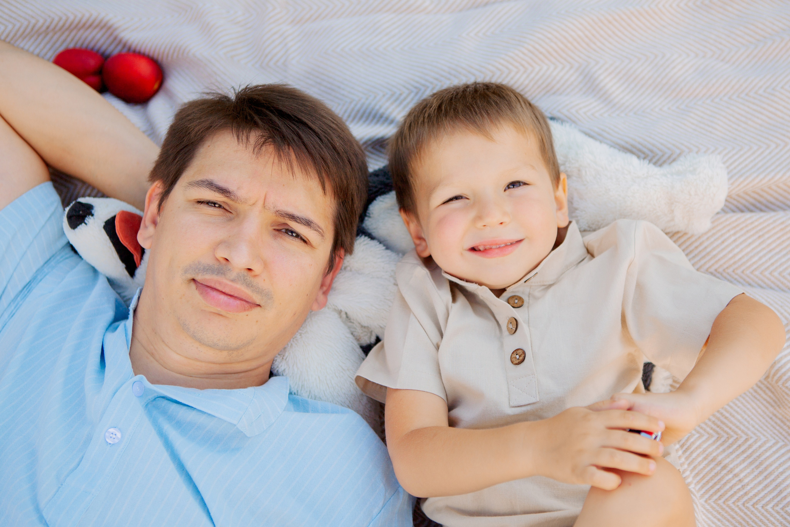 папа позирует с сыном лежа на пикнике