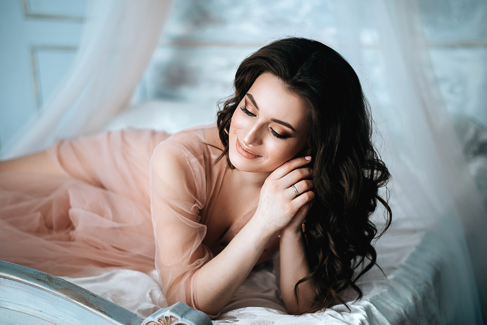 Девушка в розовом платье на кровати в красивой студии