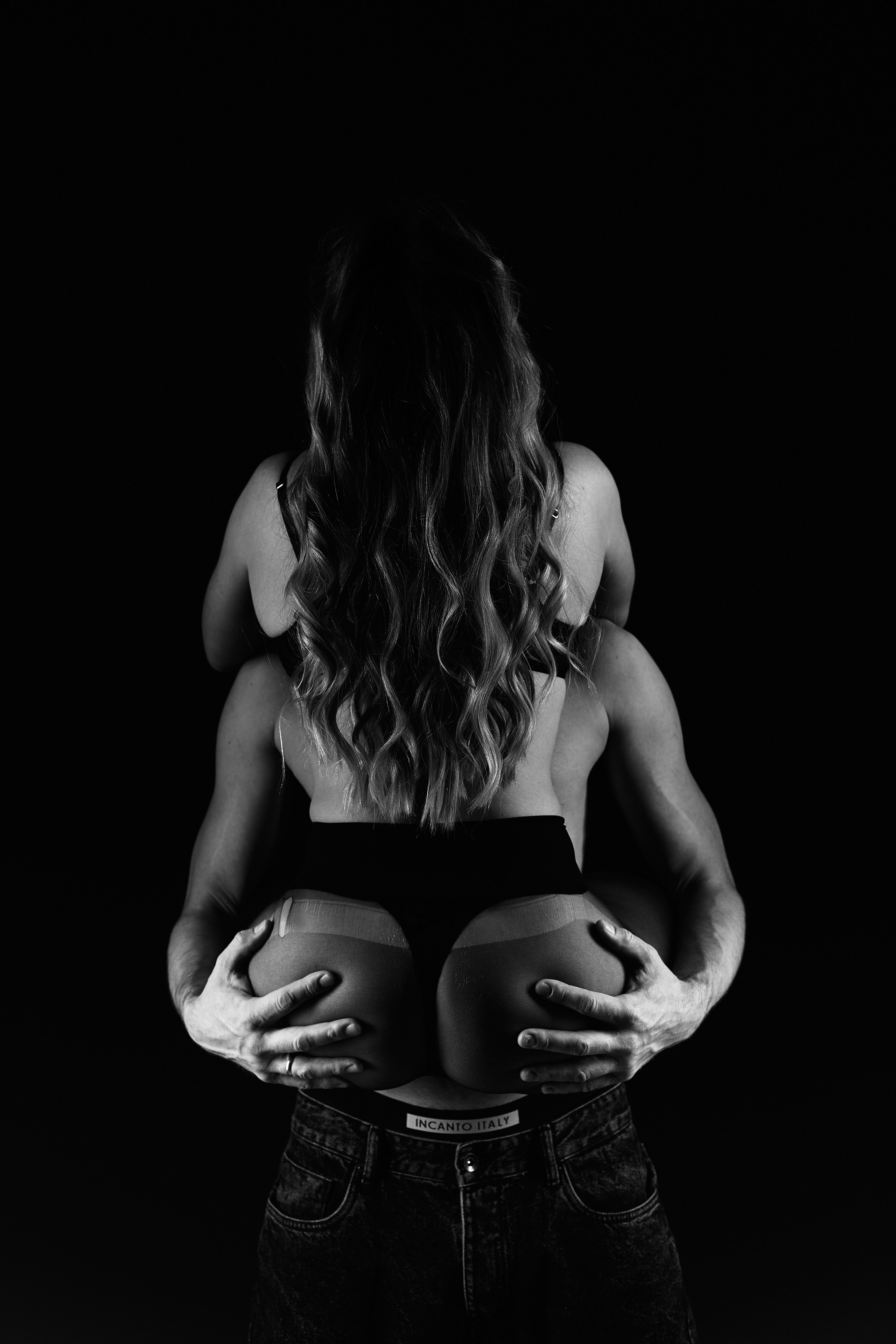 Парная ню фотосессия в Минске: полуобнажённая женщина сидит спиной к камере, мужчина держит её за бёдра, контрастные блики на фигурах