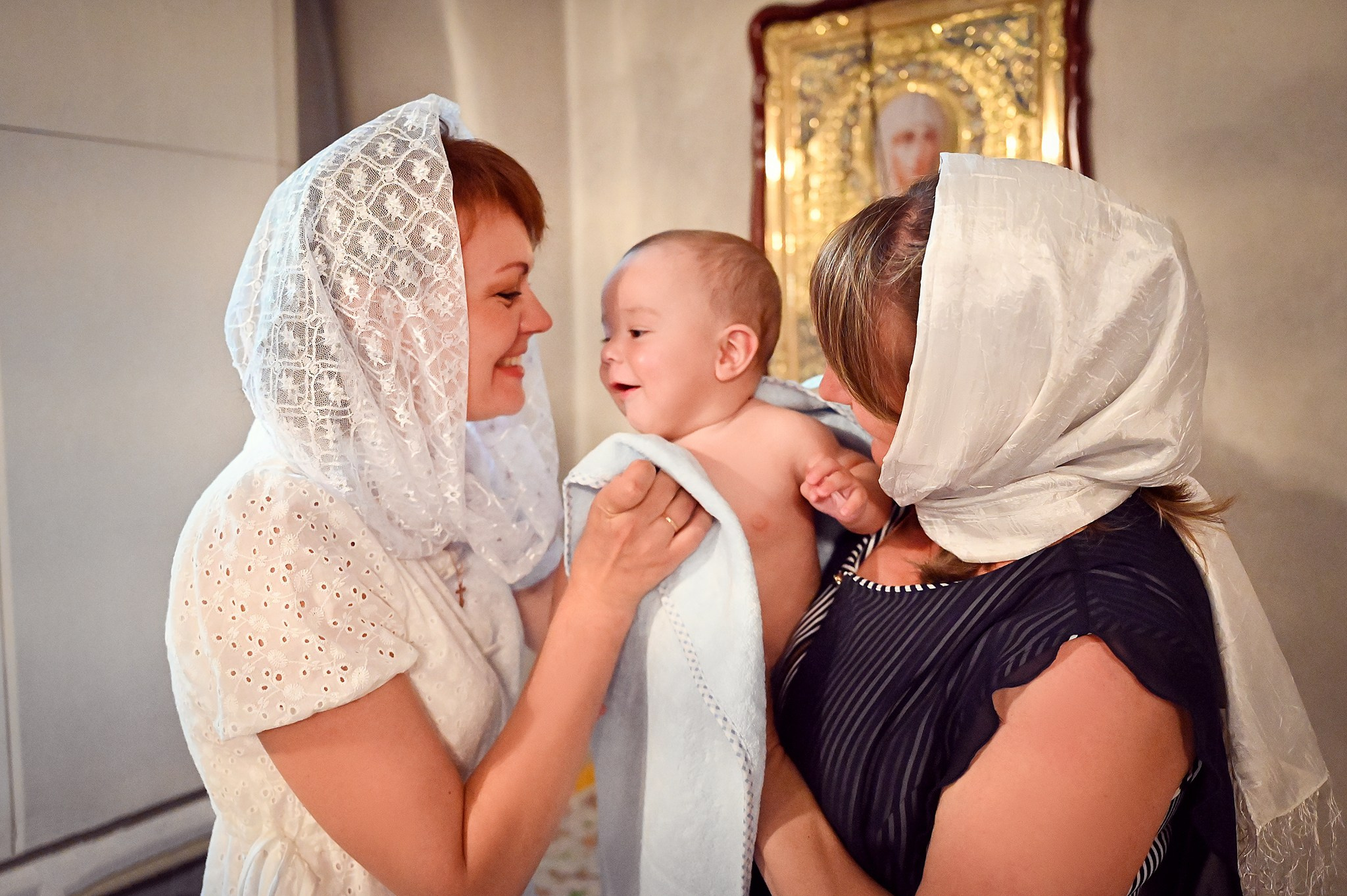 Фотосъемка в православном храме - ребенок на руках у матери и крестной