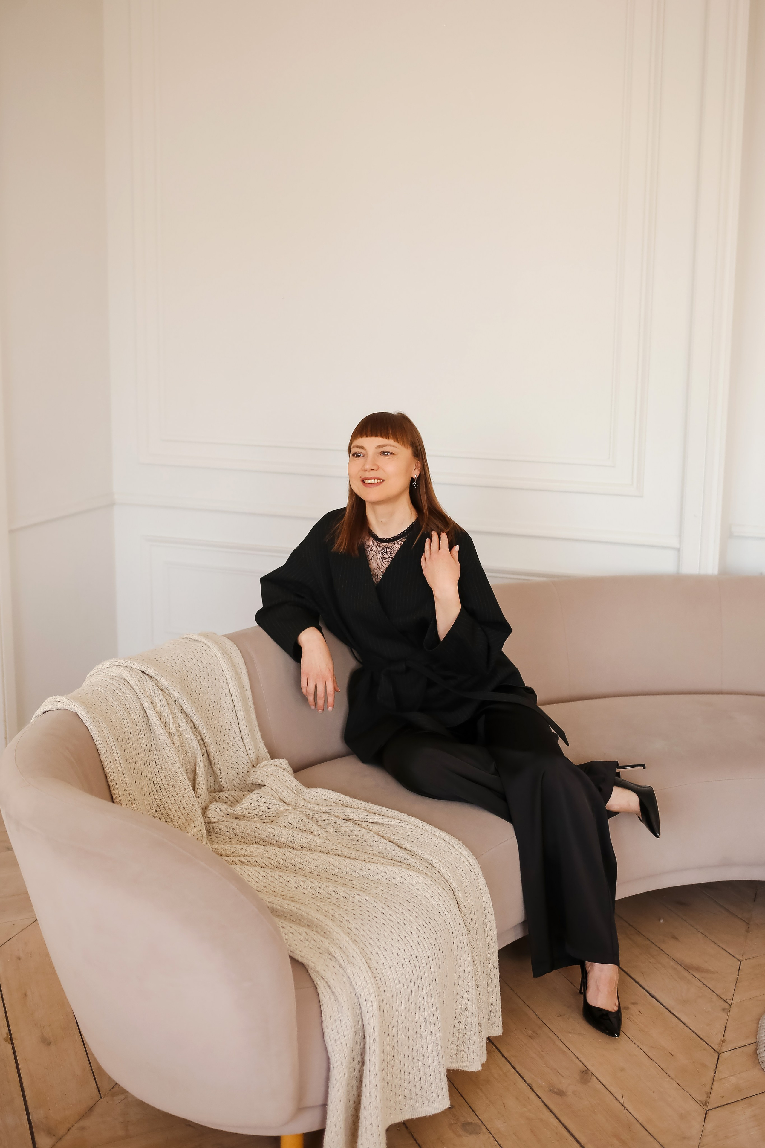 девушка в брючном костюме сидит на диване фотографируется