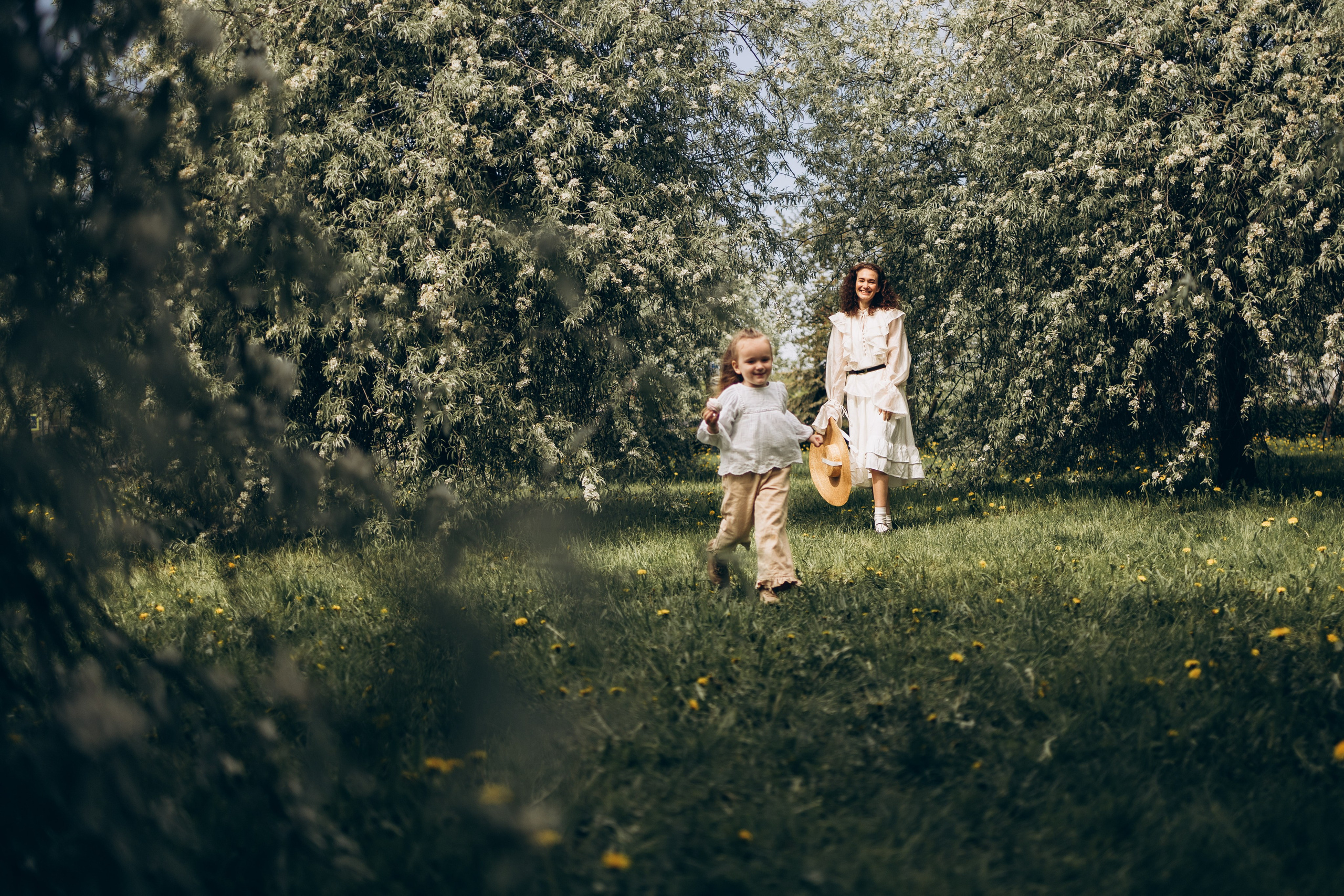 мама с дочкой бегают по яблоневому саду