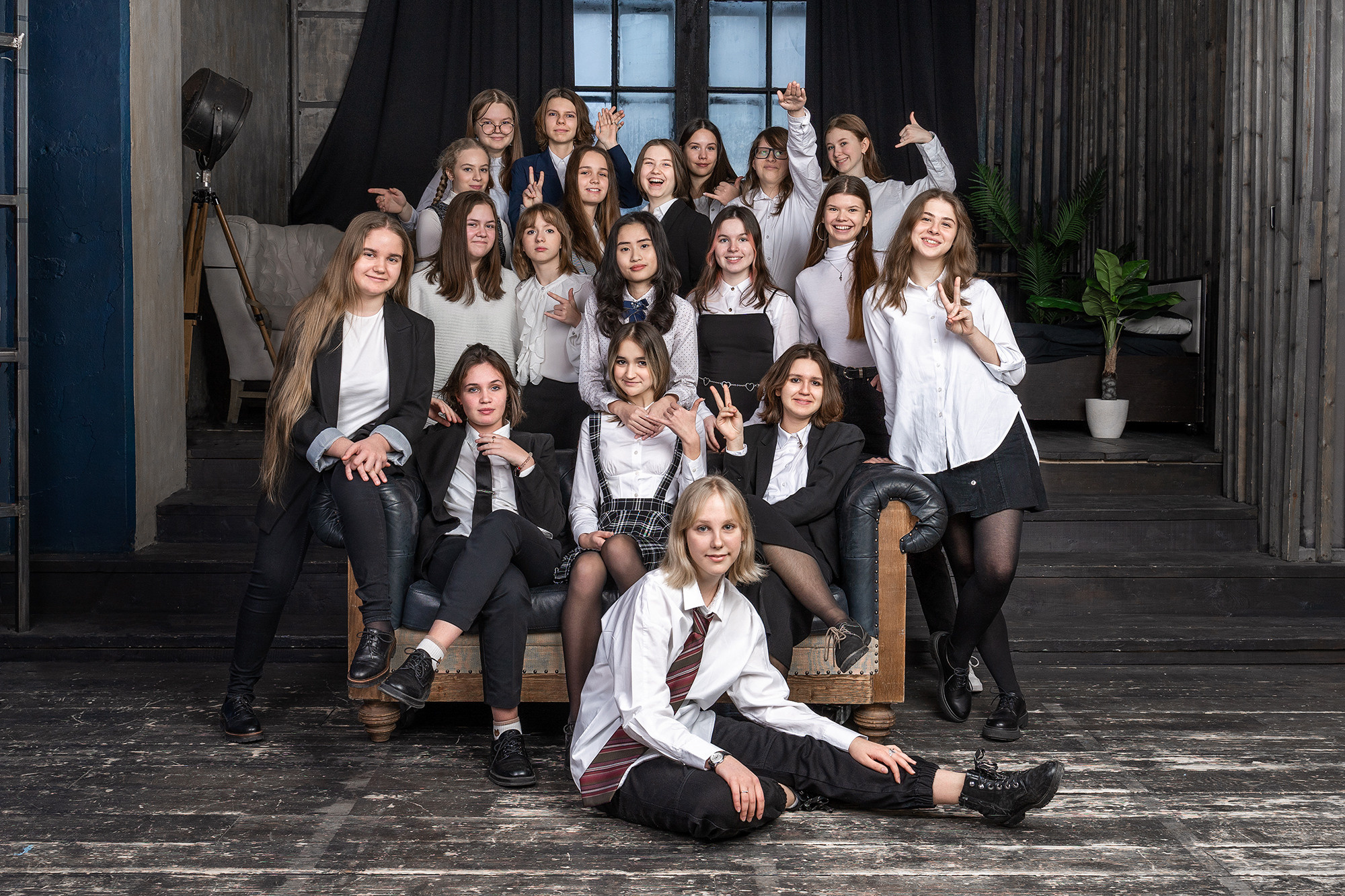 Групповое фото девушек-школьниц на небольшой лестнице на фоне окна.