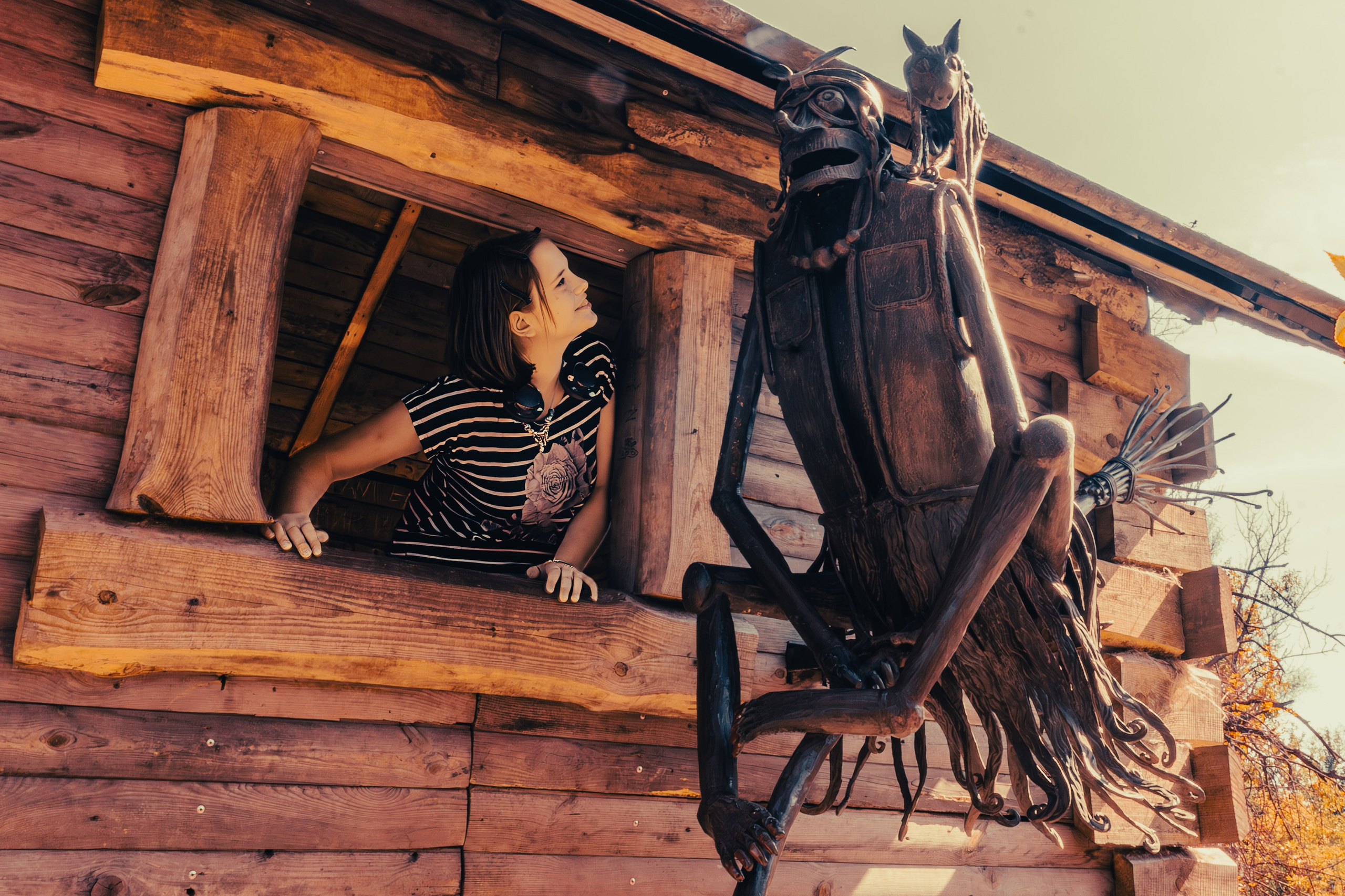 Девочка смотрит из окошка избушки на инсталляцию Бабы Яги