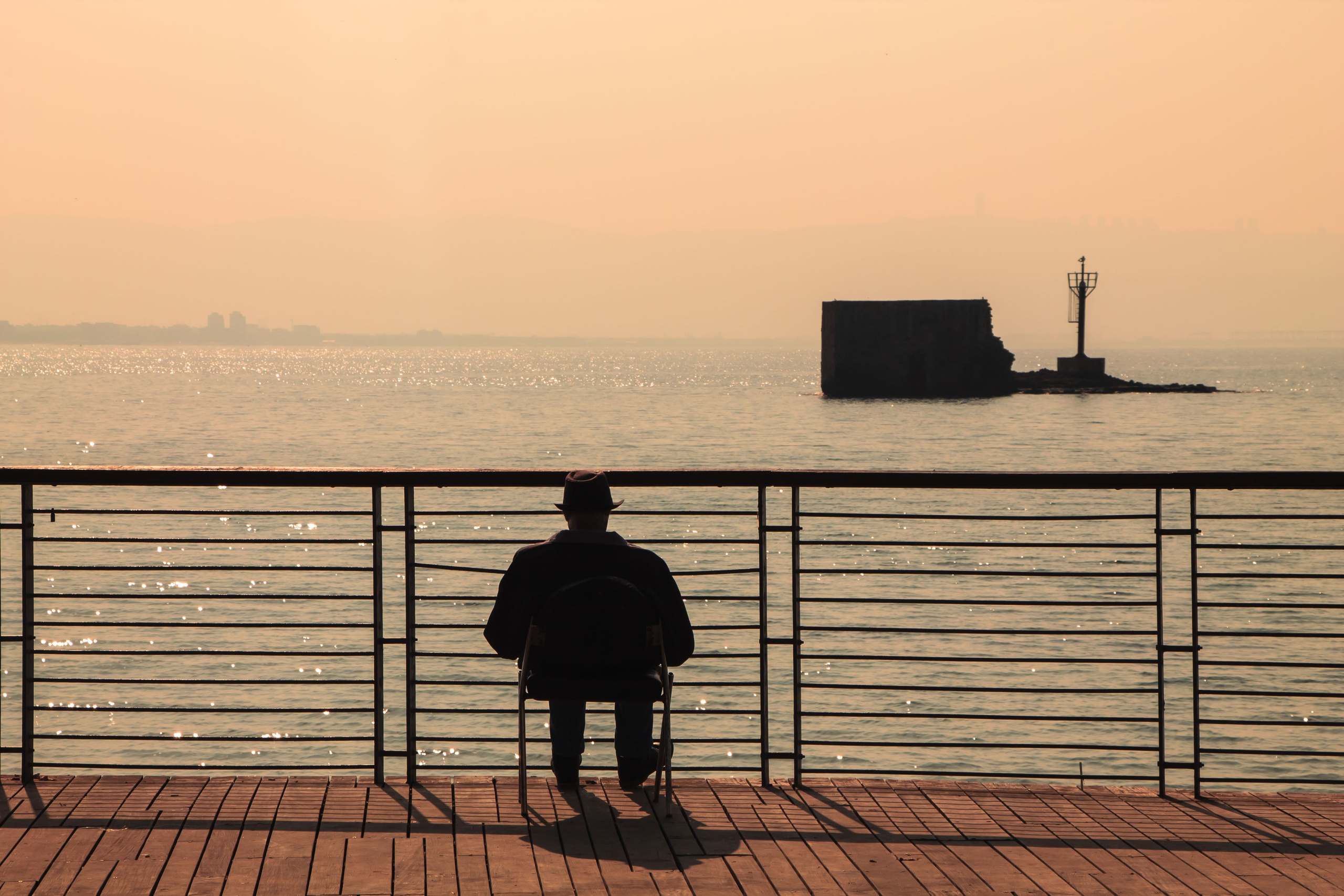 мужчины сидит возле море, на голове черная шляпа