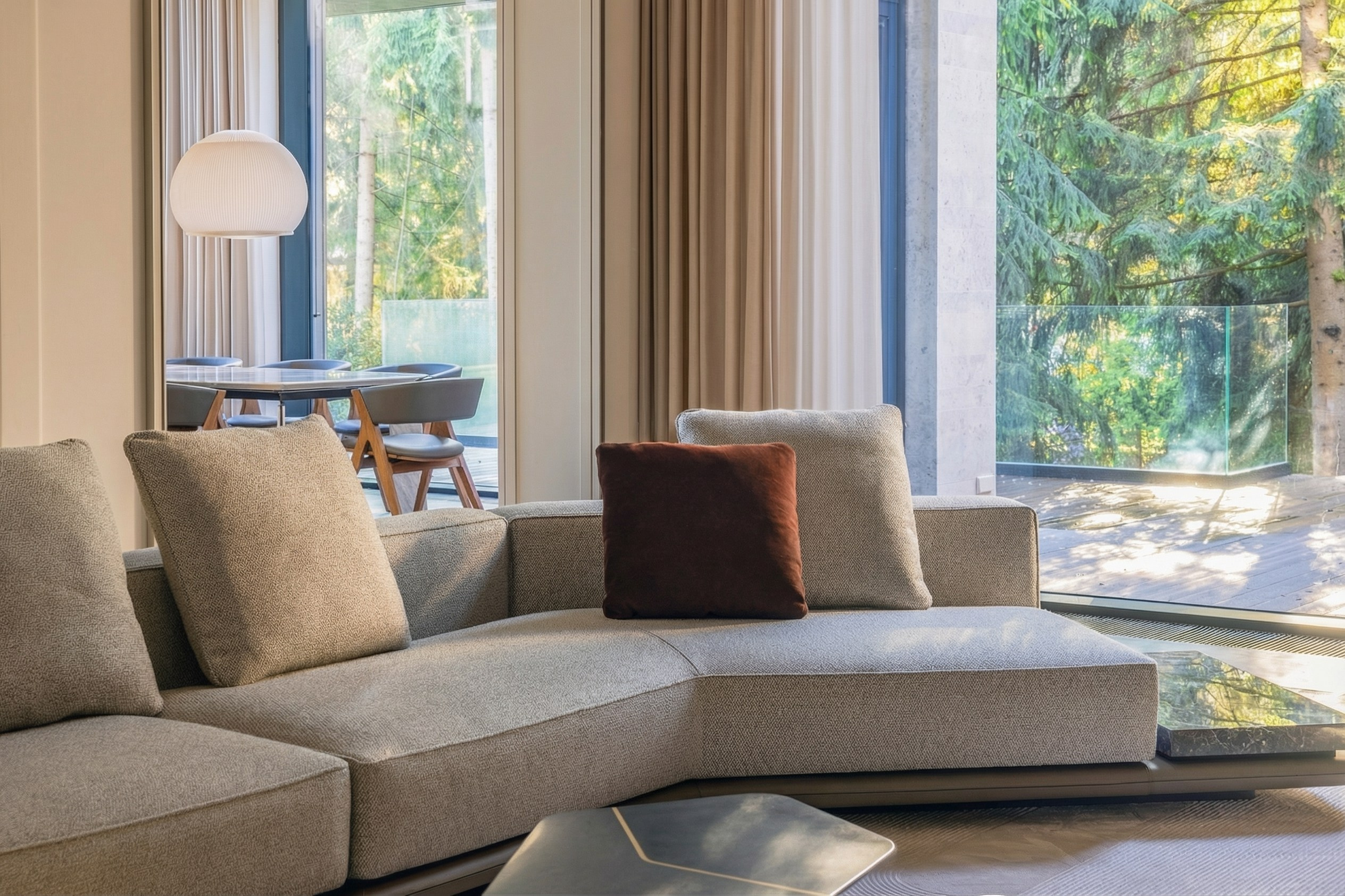 Угловая зона гостиной с панорамным видом на террасу и лес, модульный диван в нейтральных тонах с акцентным декором, проект Валерии Котович, дом 1240 м² в Подмосковье.