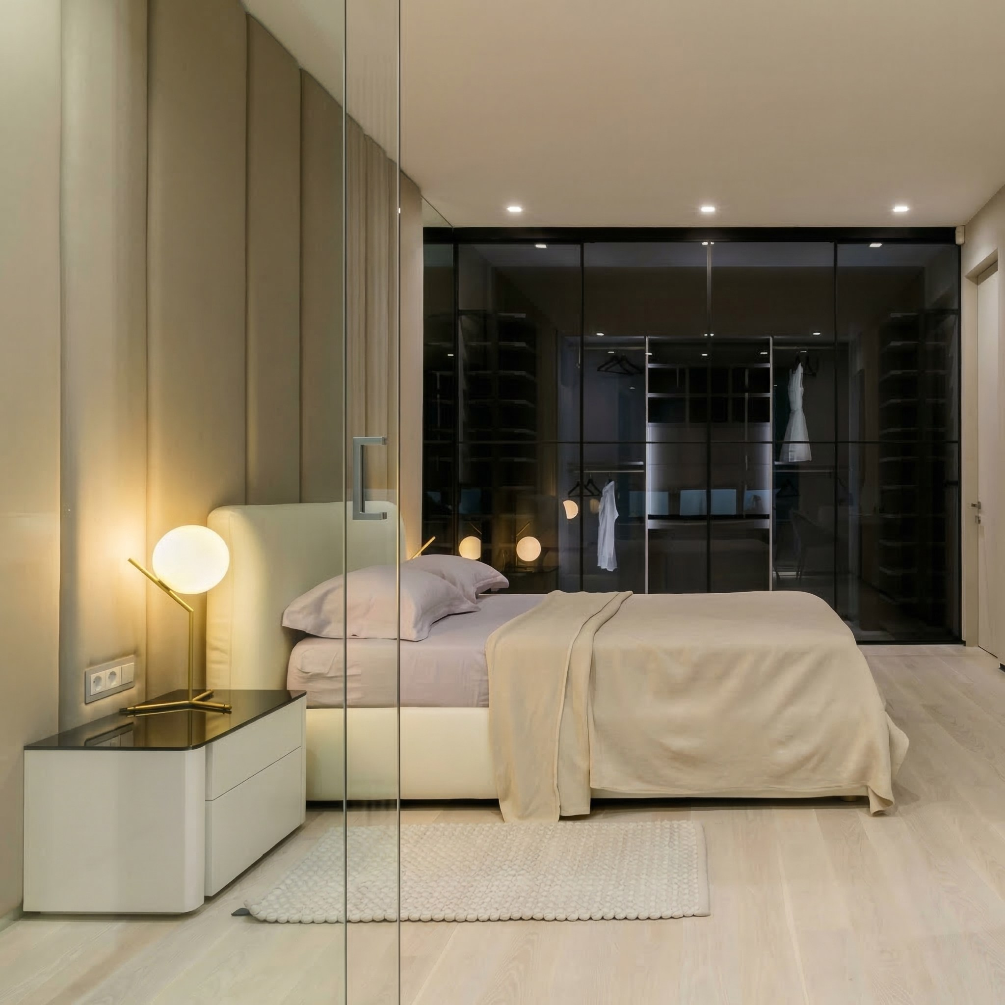 Мастер-спальня с гардеробной в реализованном проекте 118 кв.м: кровать с мягким бежевым изголовьем, дизайнерский светильник на тумбе и стеклянная гардеробная система Raumplus с подсветкой.