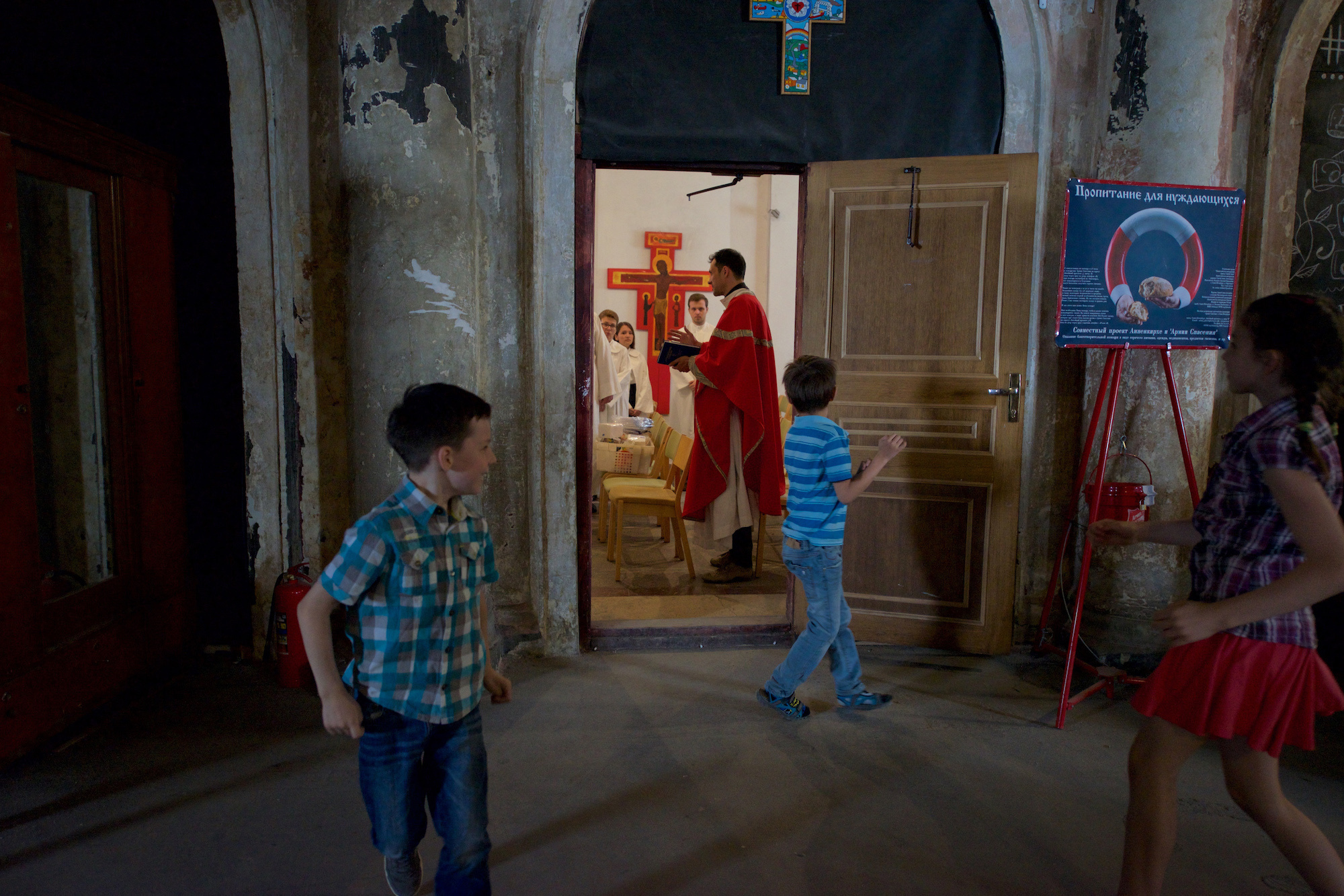 The pastor with the congregation is preparing for the service. Children run in the lobby.