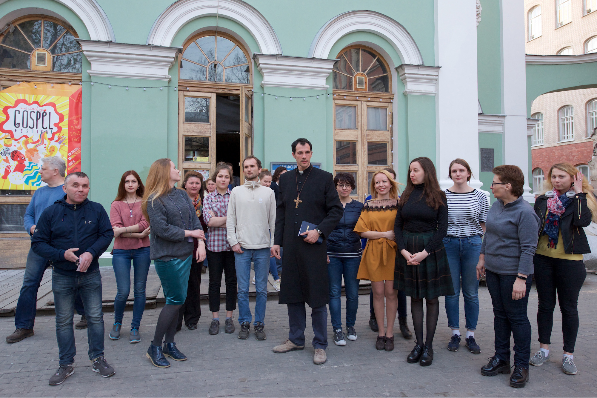 Pastor Evgeny Raskatov in front of the church in a circle of parishioners and guests.