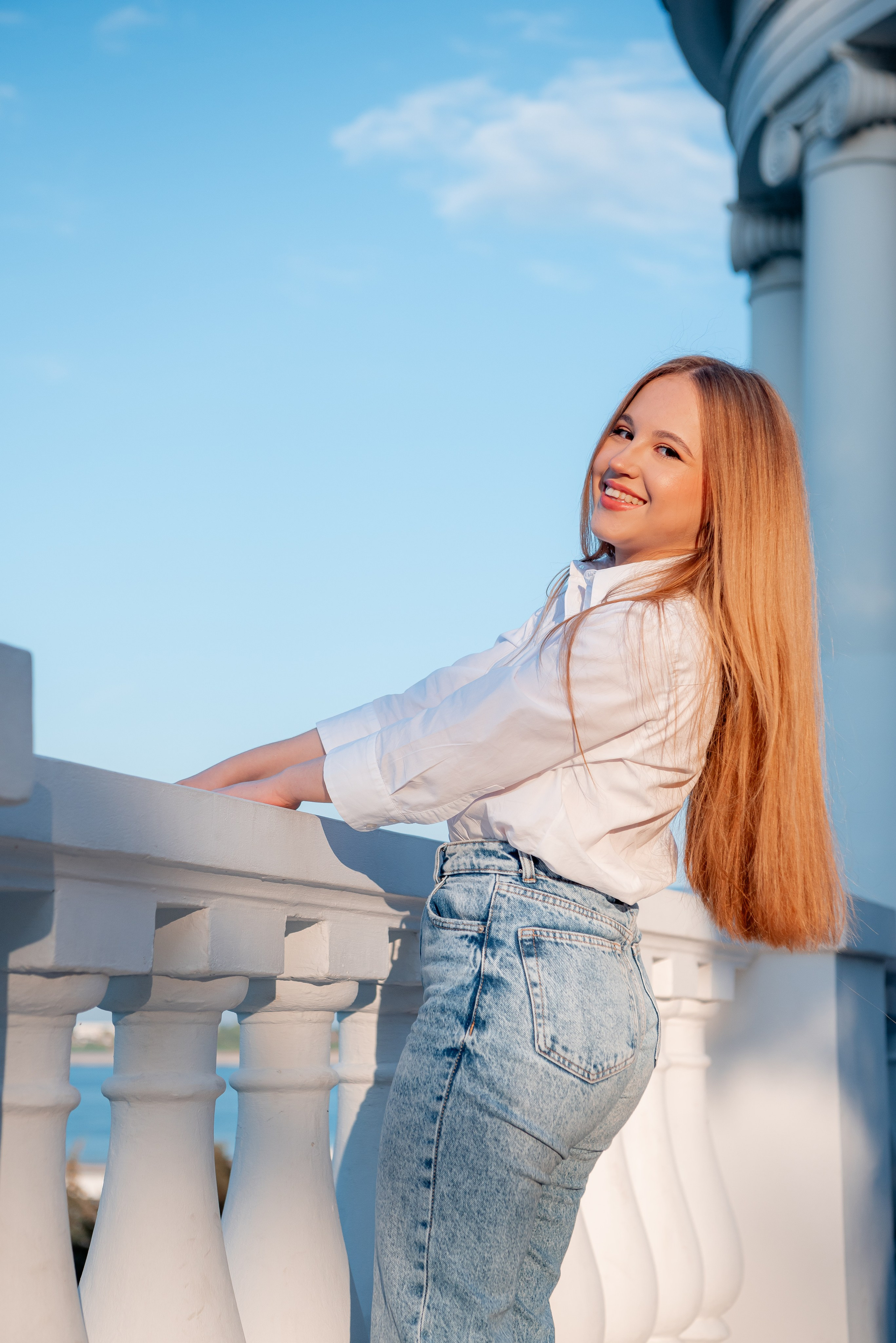 Портрет девушки в лучах закатного солнца рядом с ротондой на набережной