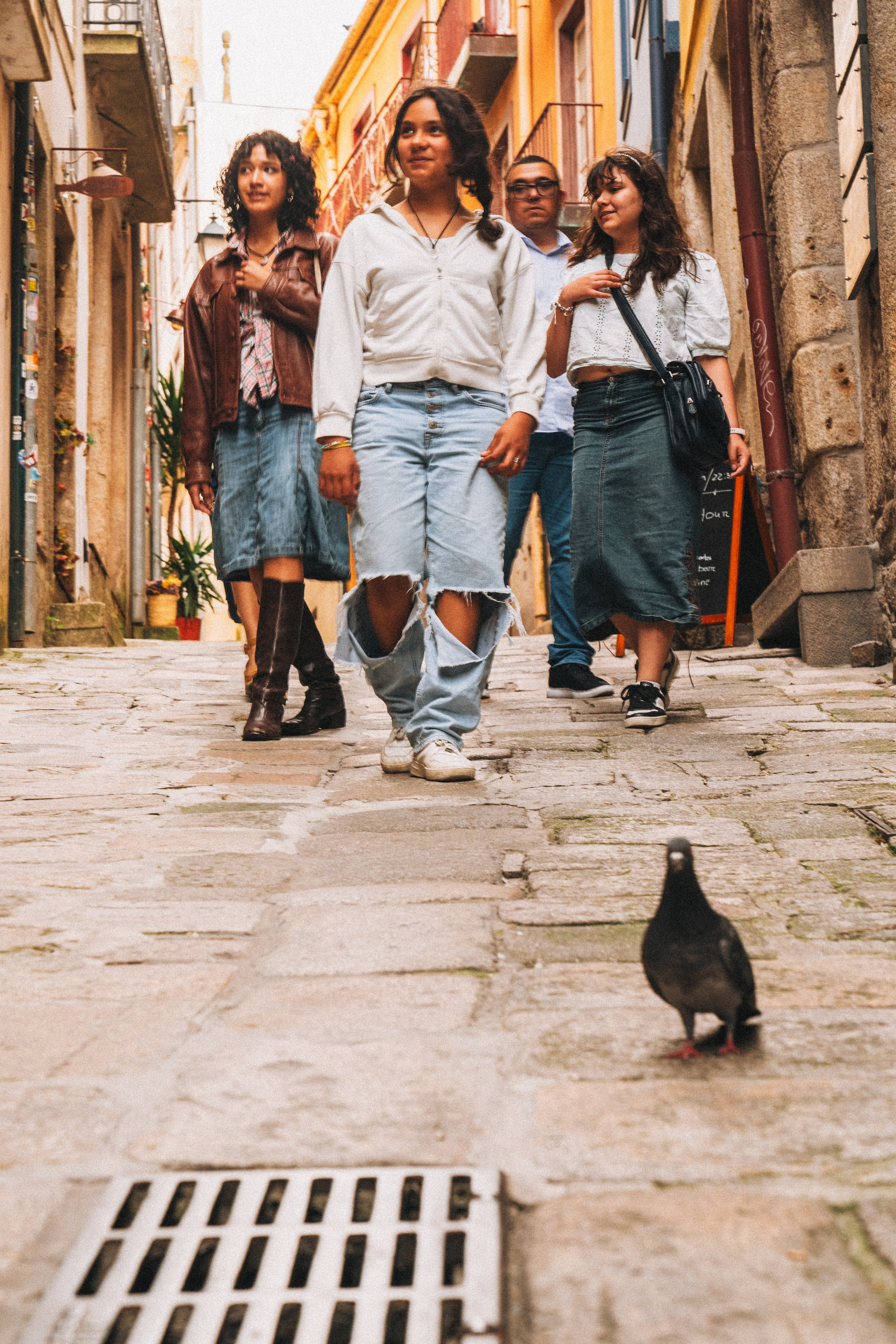 Группа людей семья влюбленные гуляет по живописной узкой улочке в Португалии, окружённой старыми домами и зеленью.