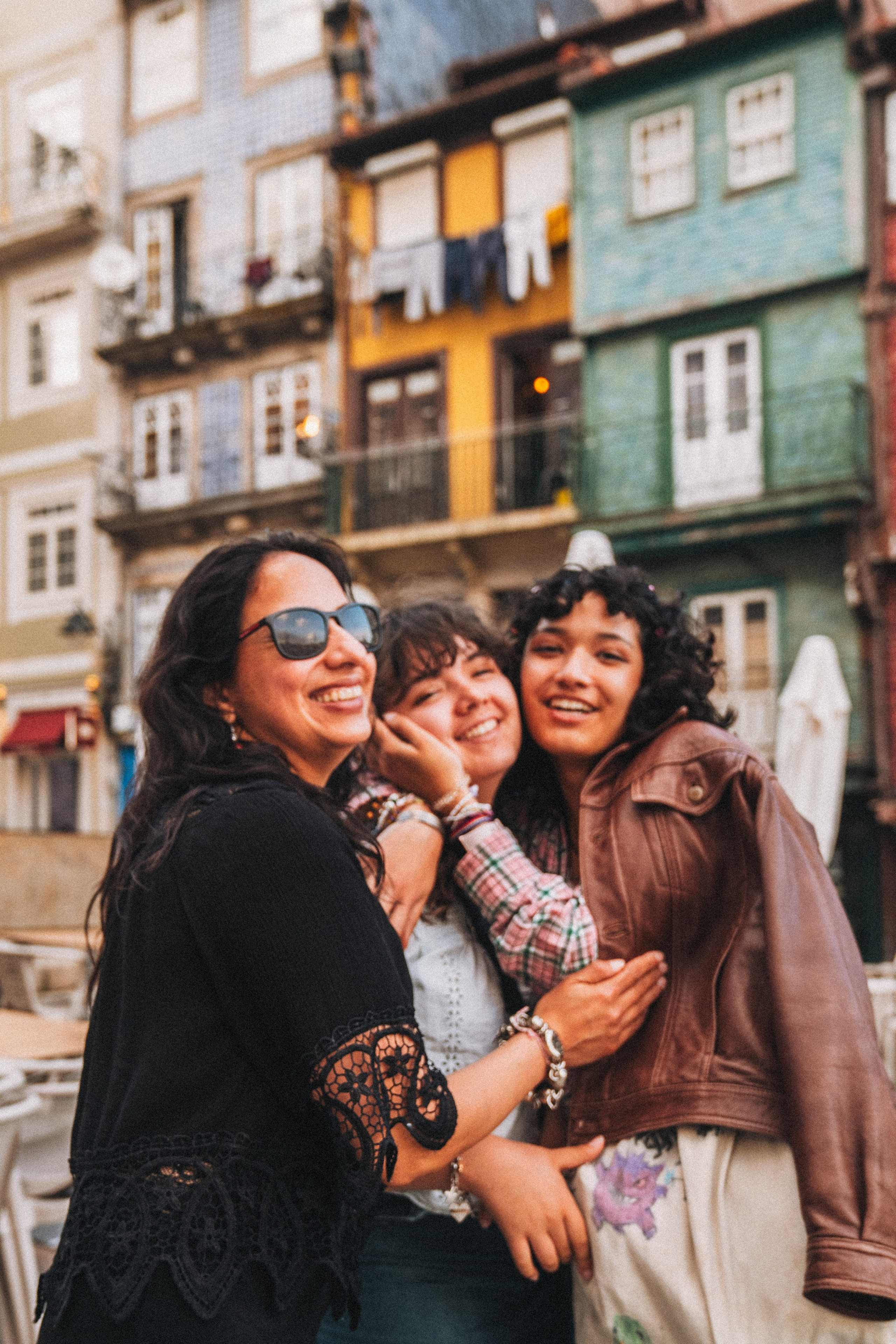 Группа людей семья влюбленные гуляет по живописной узкой улочке в Португалии, окружённой старыми домами и зеленью.