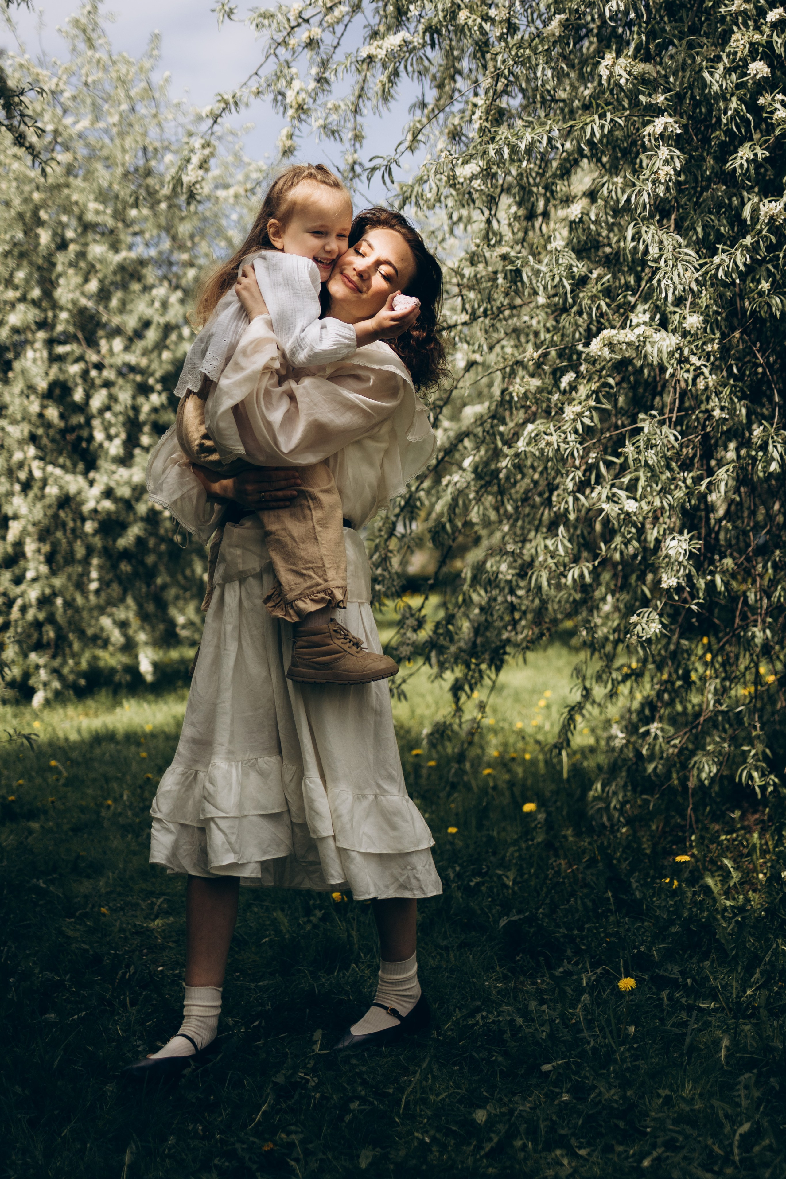 мама с дочкой в цветущем яблоневом саду гуляют и веселятся