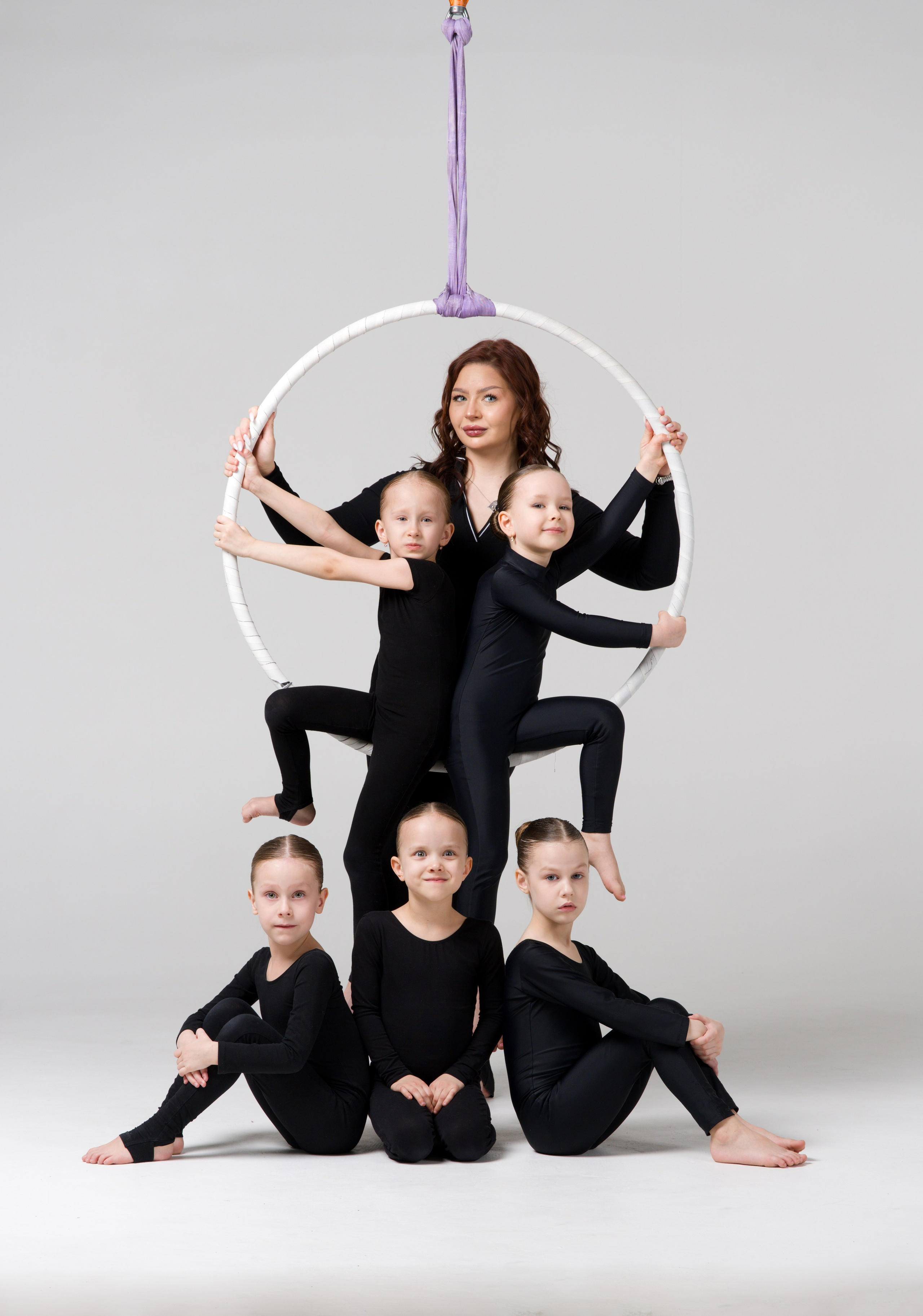 Пирамидальная постановка спортивного коллектива вокруг воздушного кольца на белой циклораме