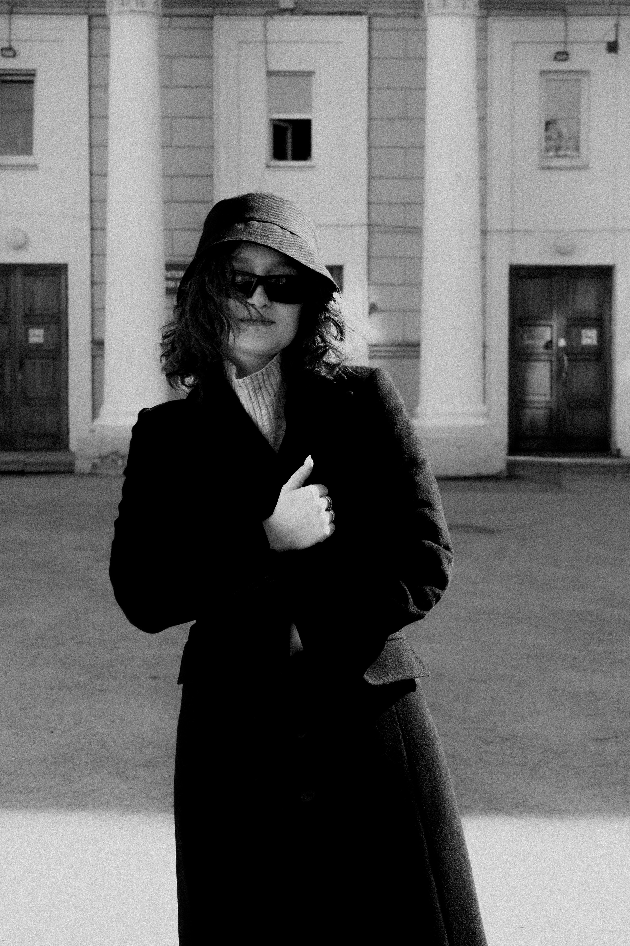 Молодая девушка в панаме и очках на фоне колонн