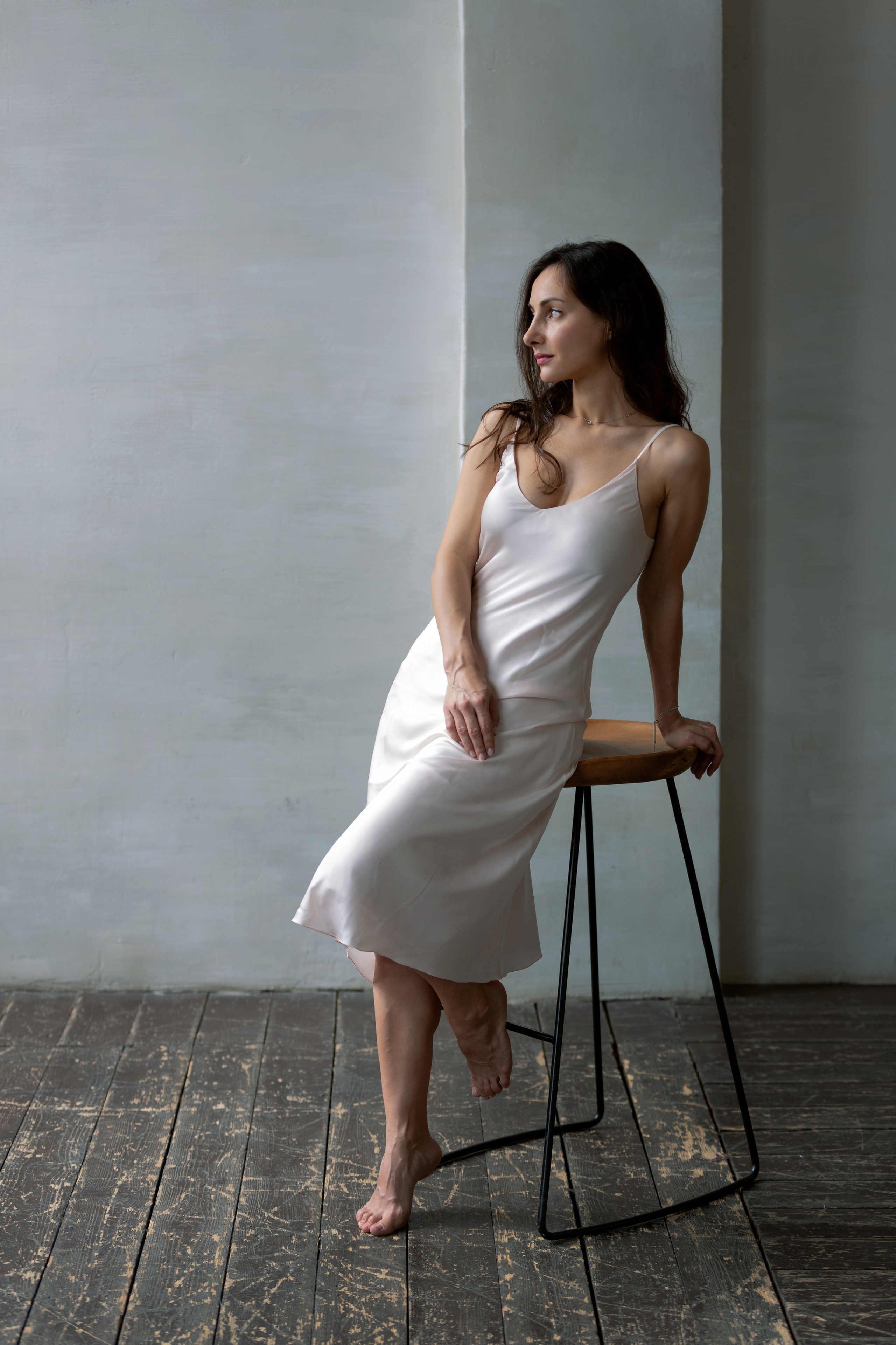 Девушка у стены в белом платье — чувственный портрет в естественном освещении.