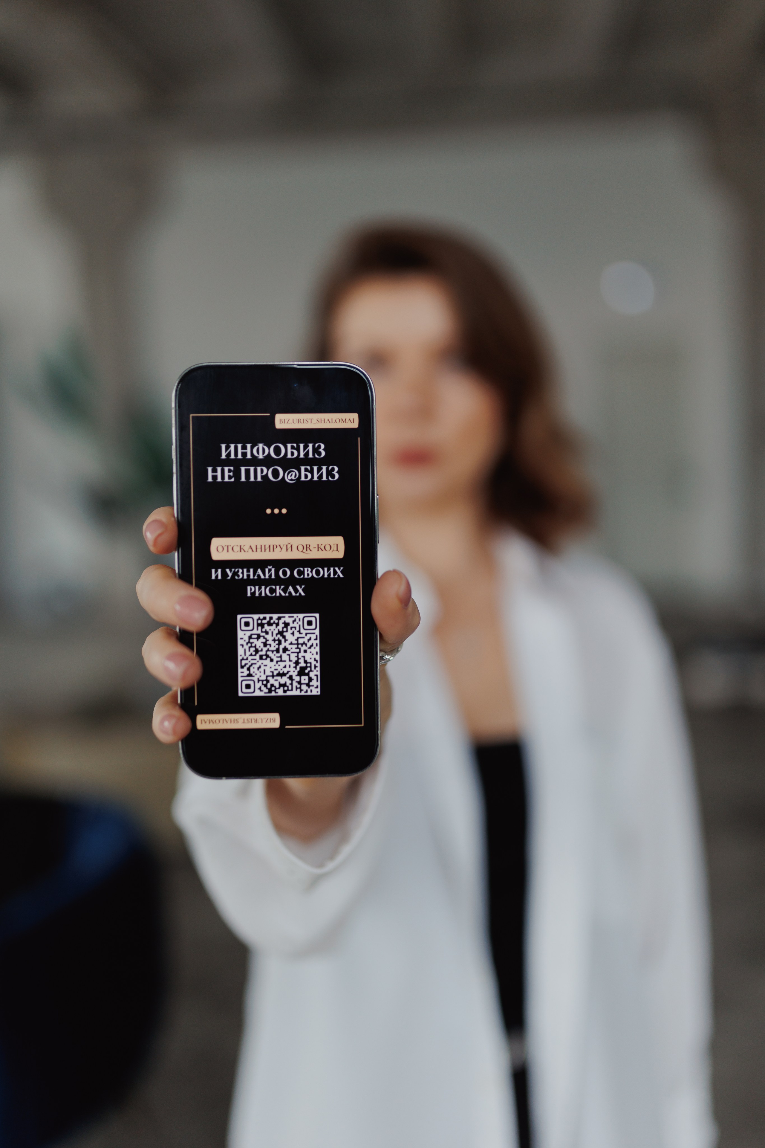 Креативная фотография: акцент на экране смартфона в руках юриста, сама модель художественно размыта. Динамичный контент для соцсетей.