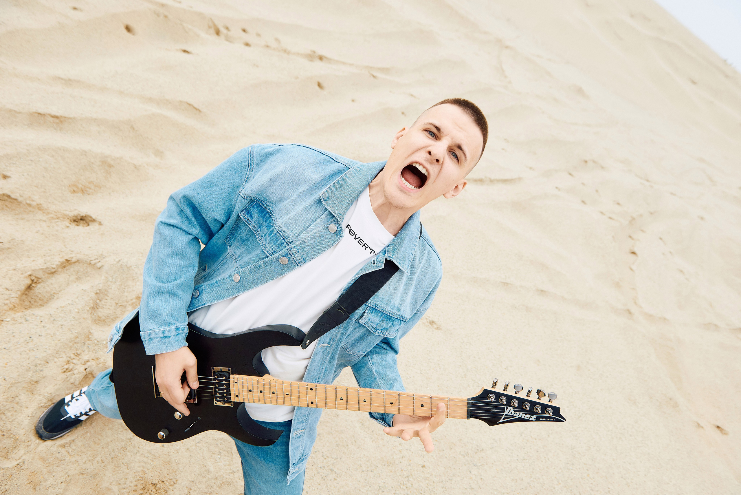 Парень играет на гитаре в пустыне и поет.