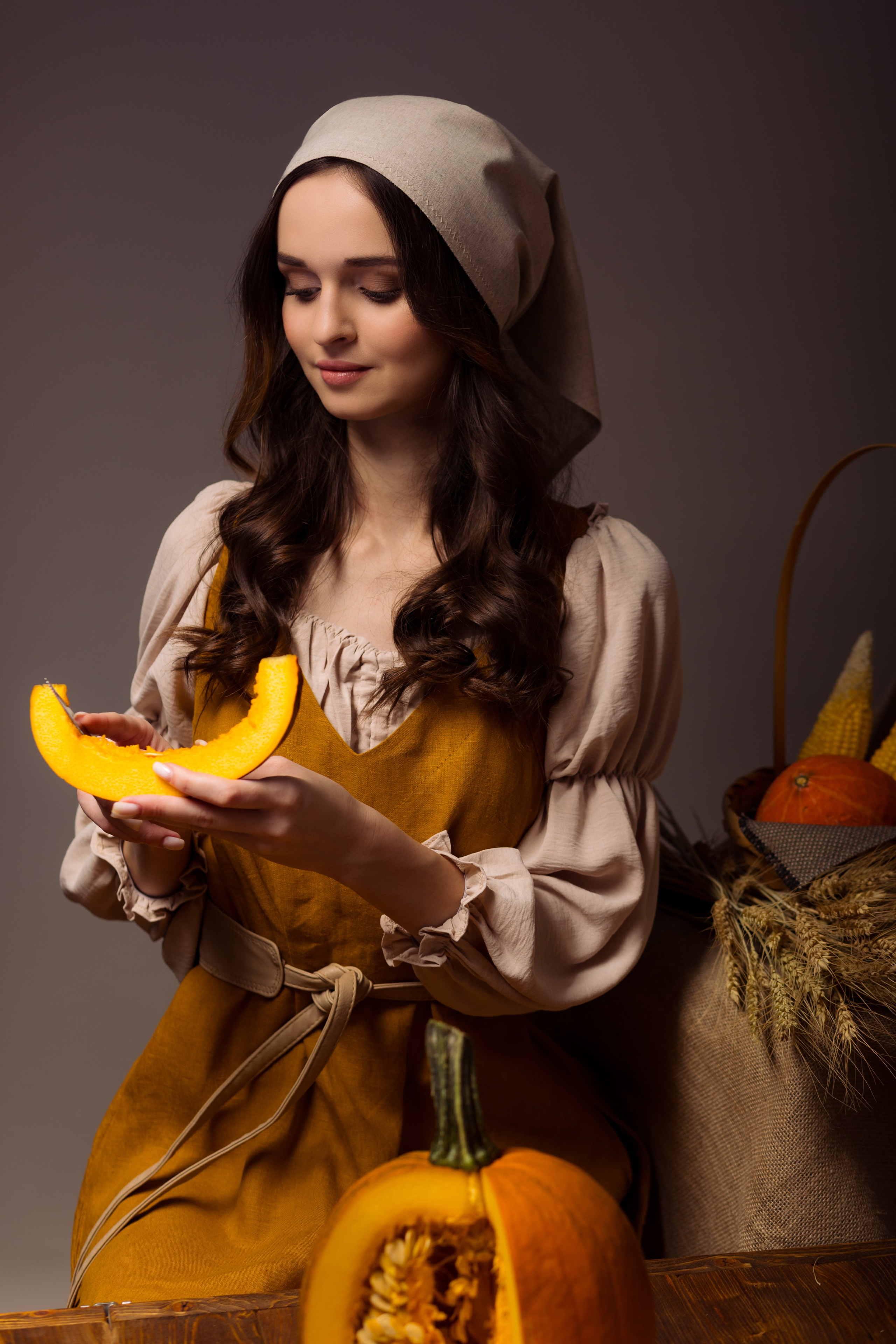 Девушка в крестьянской одежде разделывает тыкву