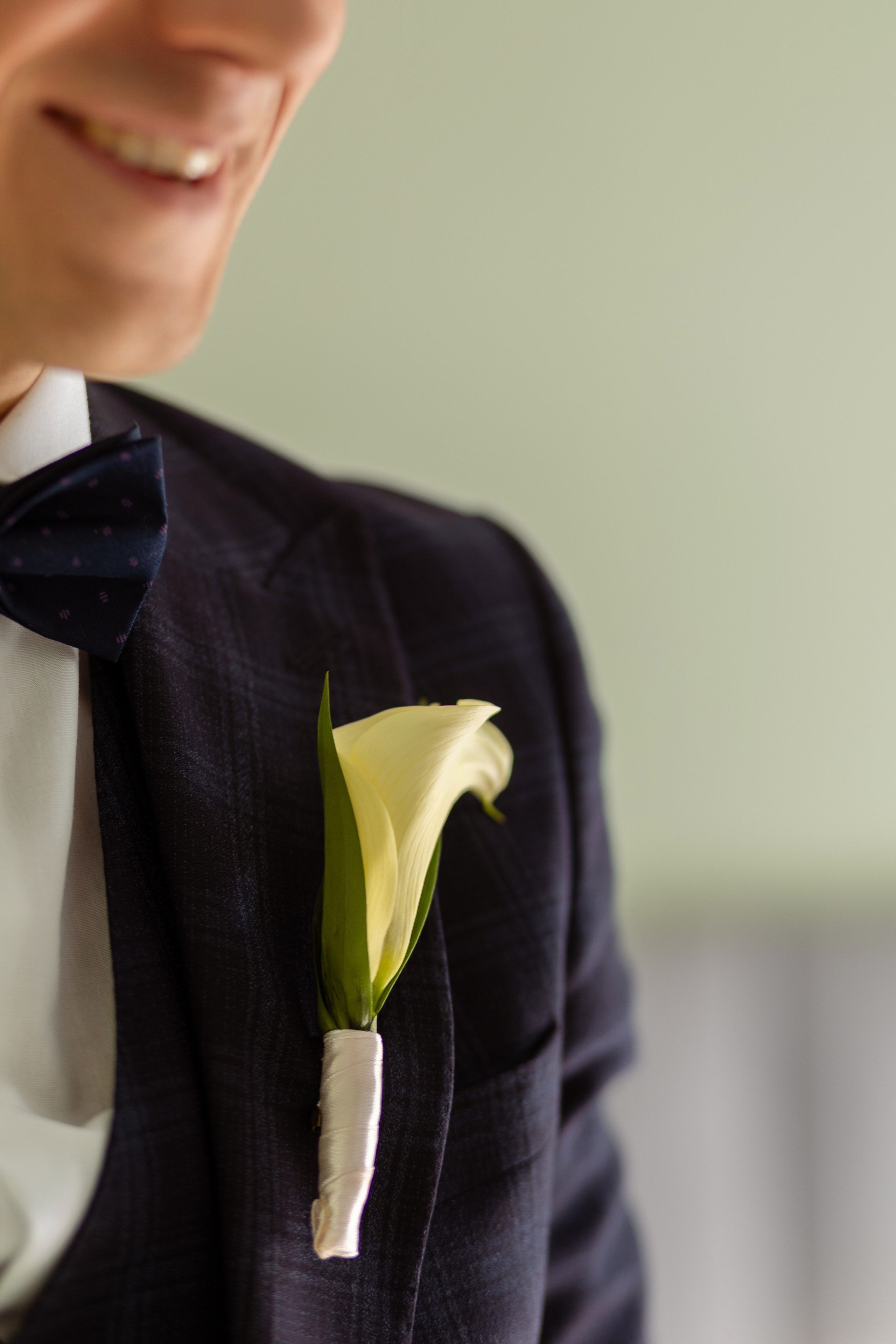 На переднем плане бутоньерка жениха на лацкане пиджака.