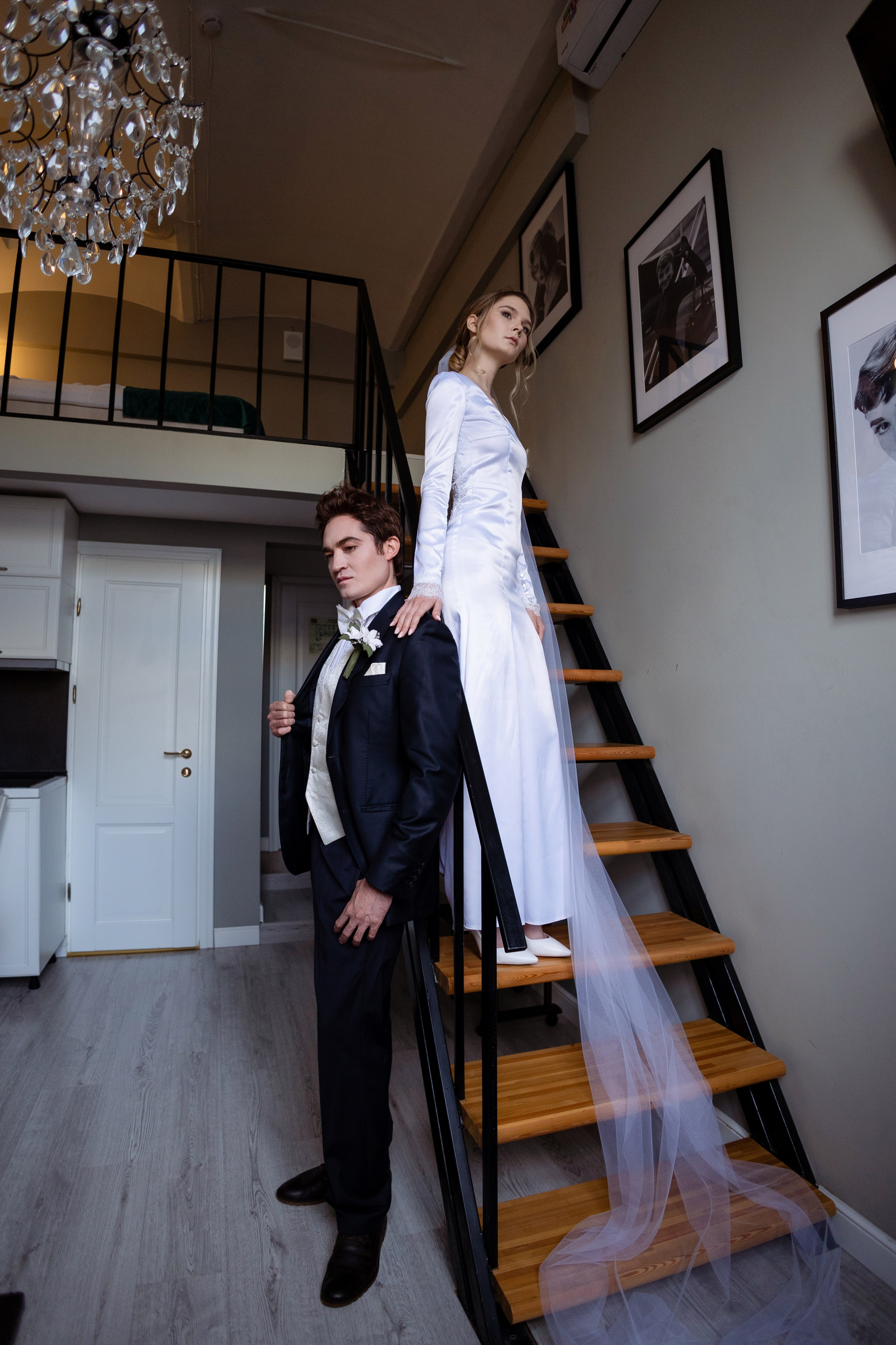Невеста стоит на лестнице, фата струится по ступеням.